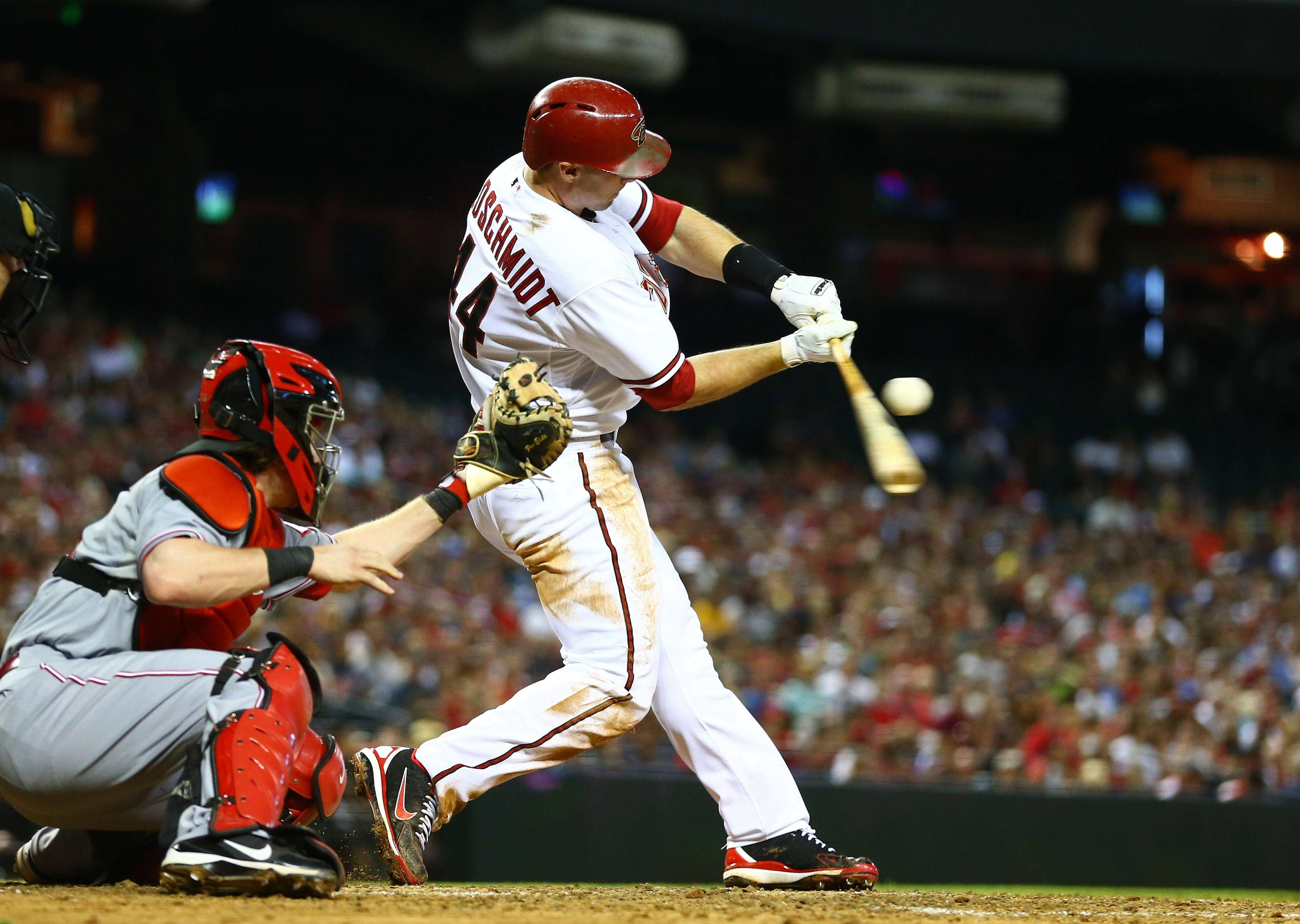 Paul Goldschmidt 桌布 壁紙 — 戴紅色頭盔的棒球選手在夜間比賽中揮棒擊球，捕手蹲在他身後。