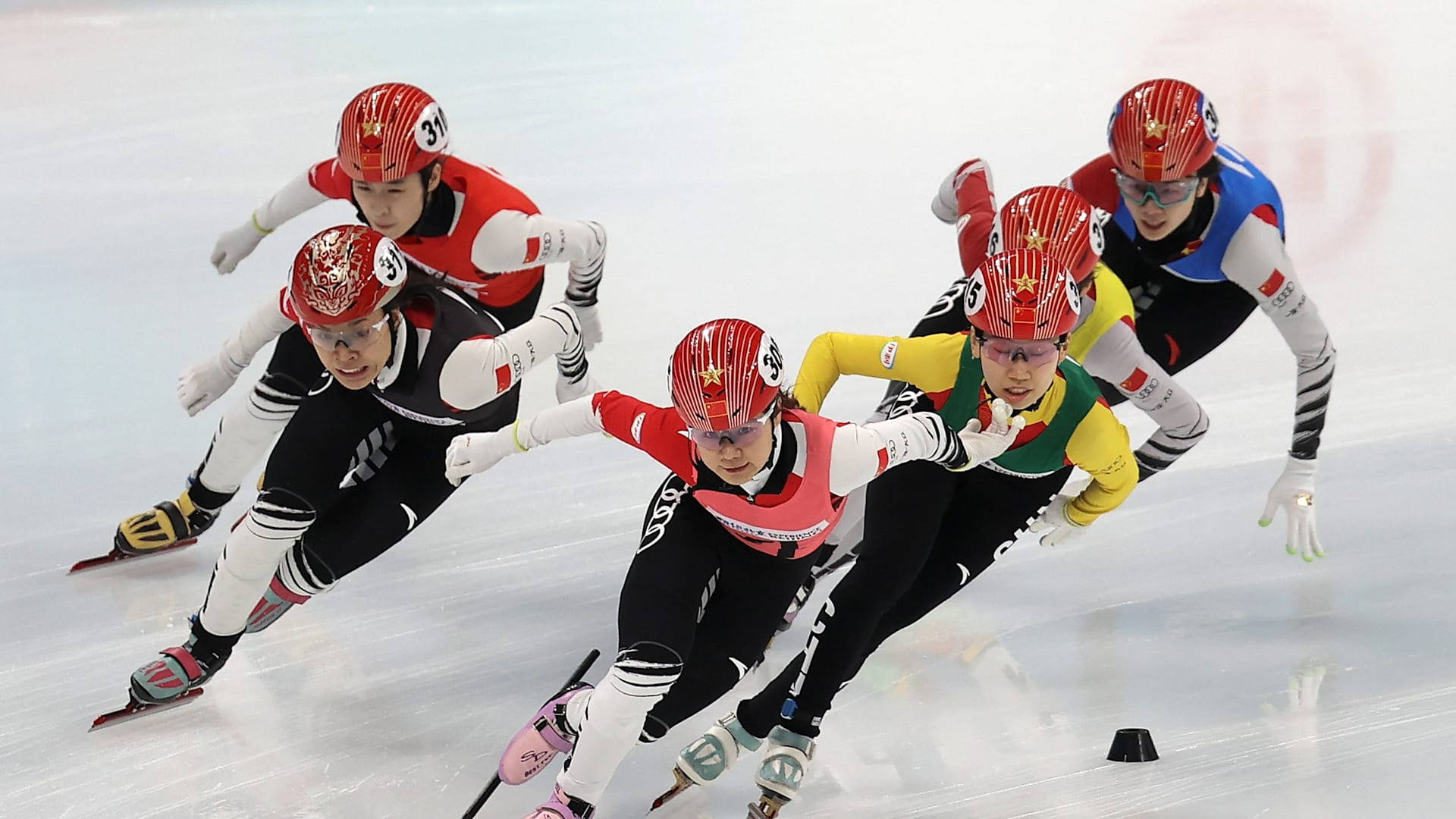 Winter Olympics 桌布 壁紙 — 戴紅色頭盔的速度滑冰選手在冰上激烈競賽，表情專注，姿勢動感。