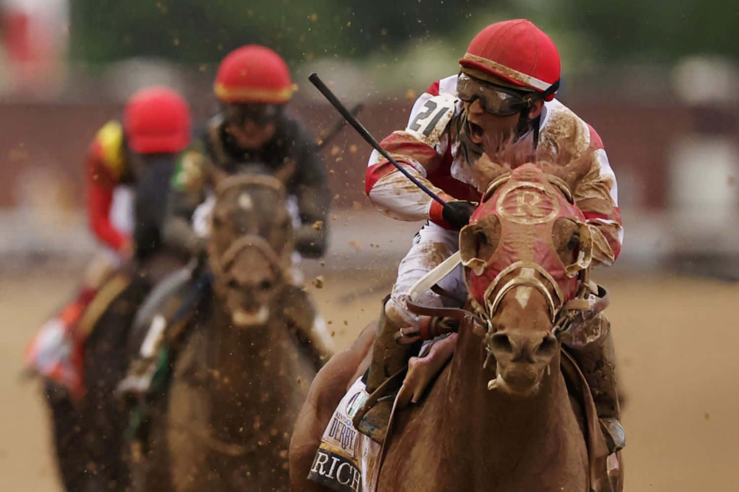 Kentucky Derby 桌布 壁紙 — 戴紅色頭盔的騎師在泥濘的馬匹於激烈賽馬中衝刺時，激烈地尖叫。