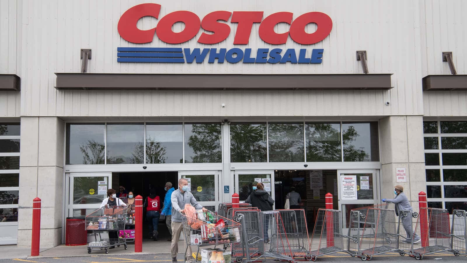 Costco 桌布 壁紙 — 戴著口罩的人們推著裝滿商品的購物車離開Costco Wholesale商店。