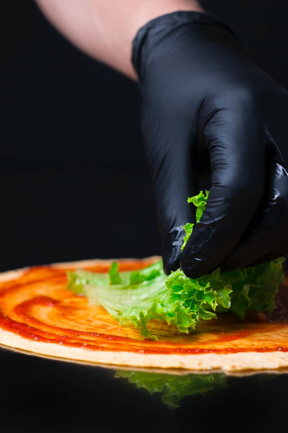 Vegetables 桌布 壁紙 — 戴著手套的手將脆綠的生菜放在塗滿鮮紅醬汁的玉米餅上，背景是深色反光表面。