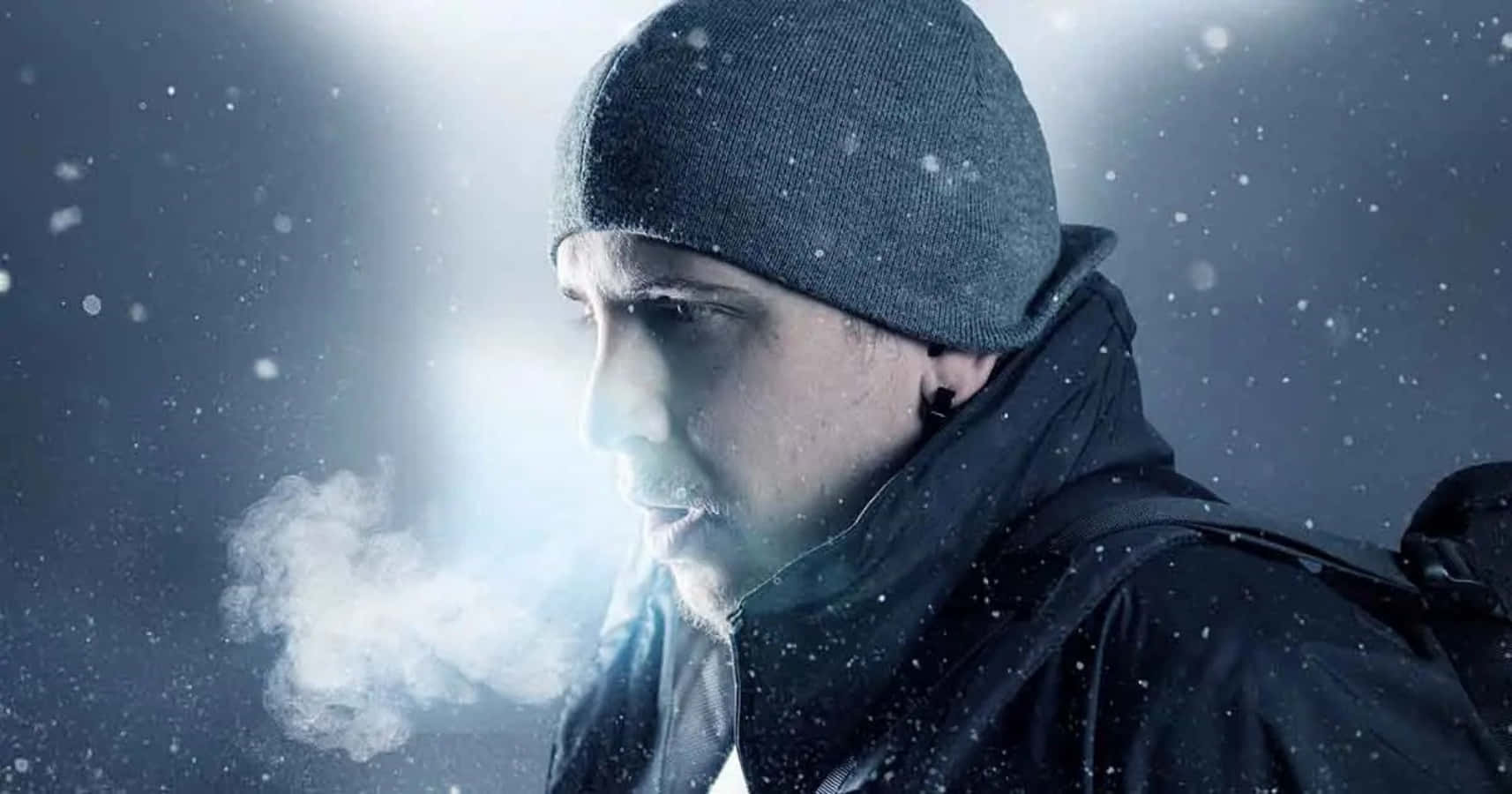 戴著毛帽和帽子的男子在雪中抽菸 壁紙