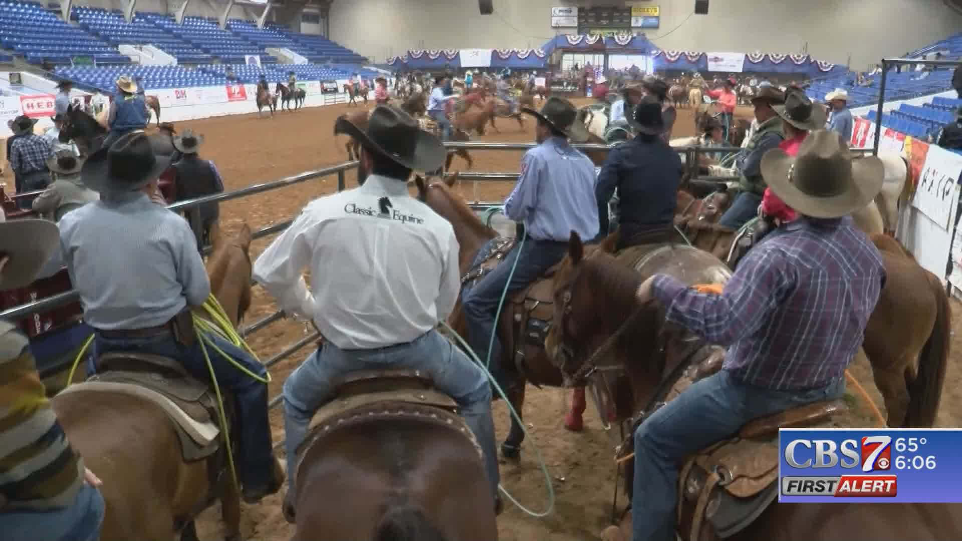 Team Roping 桌布 壁紙 — 戴著牛仔帽和牛仔褲的騎手在擠滿人的室內競技場中騎在馬背上參加牛仔競技活動。