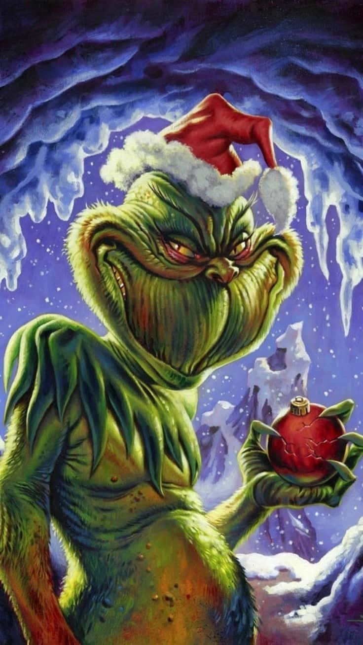 The Grinch 桌布 壁紙 — 戴著紅色聖誕帽的鬼靈精在黑暗暴風雨的天空下，手持破裂的紅色裝飾品，背景是冰冷的雪景。