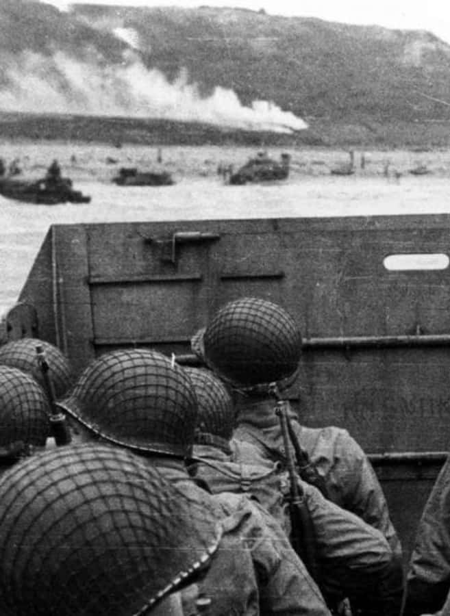 Ww2 iPhone 桌布 壁紙 — 戴頭盔的士兵從登陸艇的坡道上方窺視，遠處灘頭陣地升起煙霧，正值戰時兩棲突擊。