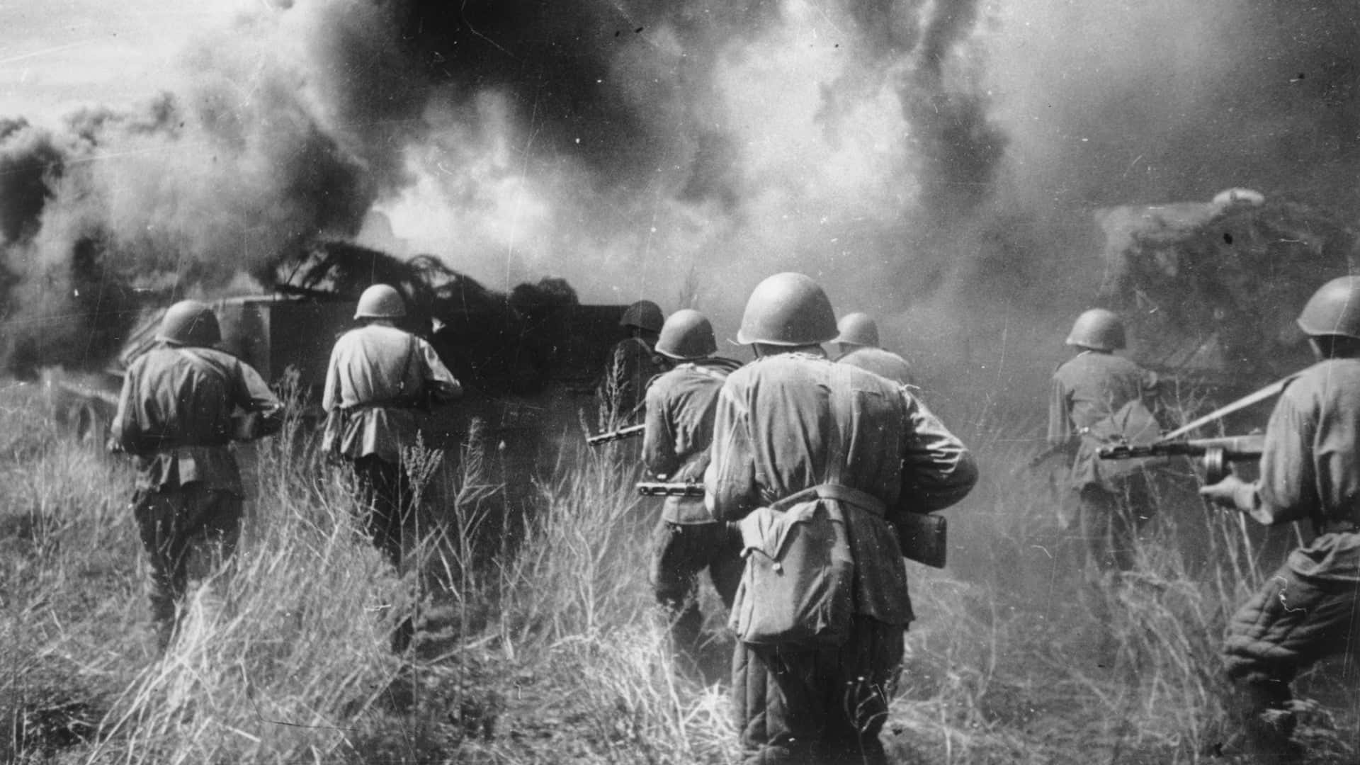 Dark War 桌布 壁紙 — 戴頭盔的士兵穿過高草前進，戰場上一輛燃燒的坦克冒出濃煙。