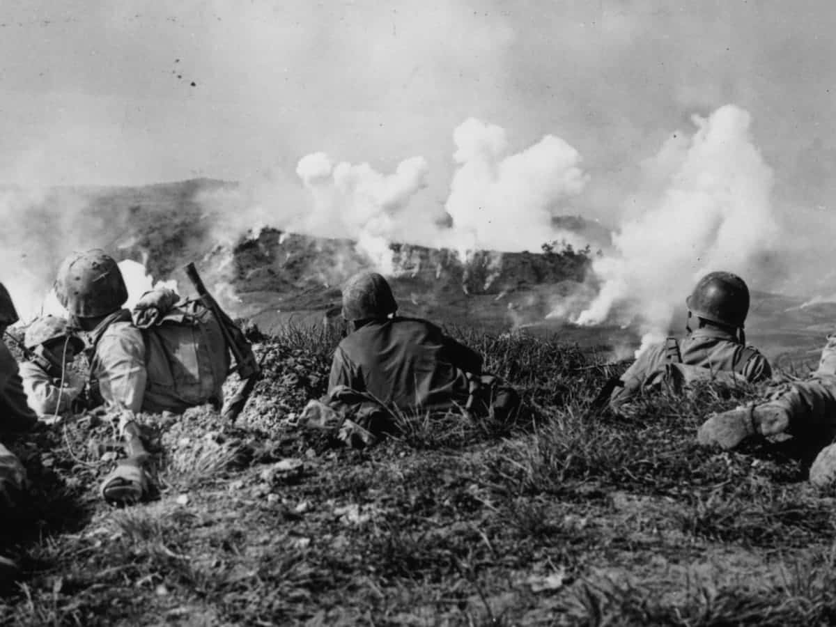 Ww2 桌布 壁紙 — 戴頭盔的士兵蹲在泥濘的戰壕中，爆炸和煙霧在他們身後的戰場上爆發。
