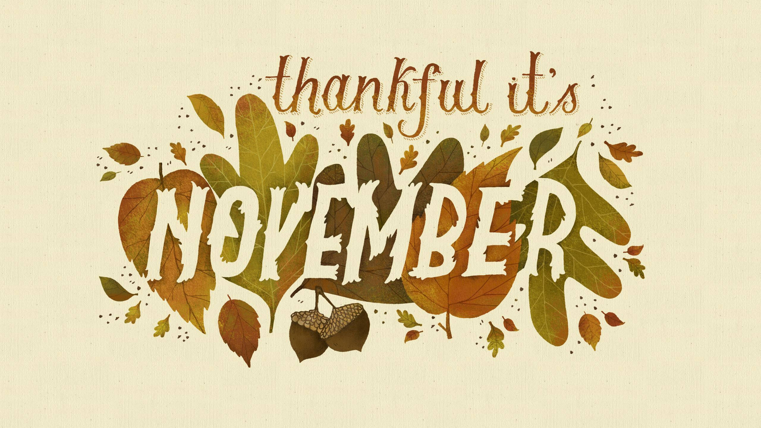 十一月 桌布 壁紙 — 手寫短語 thankful it's november 被秋葉和橡子環繞，背景為紋理奶油色。