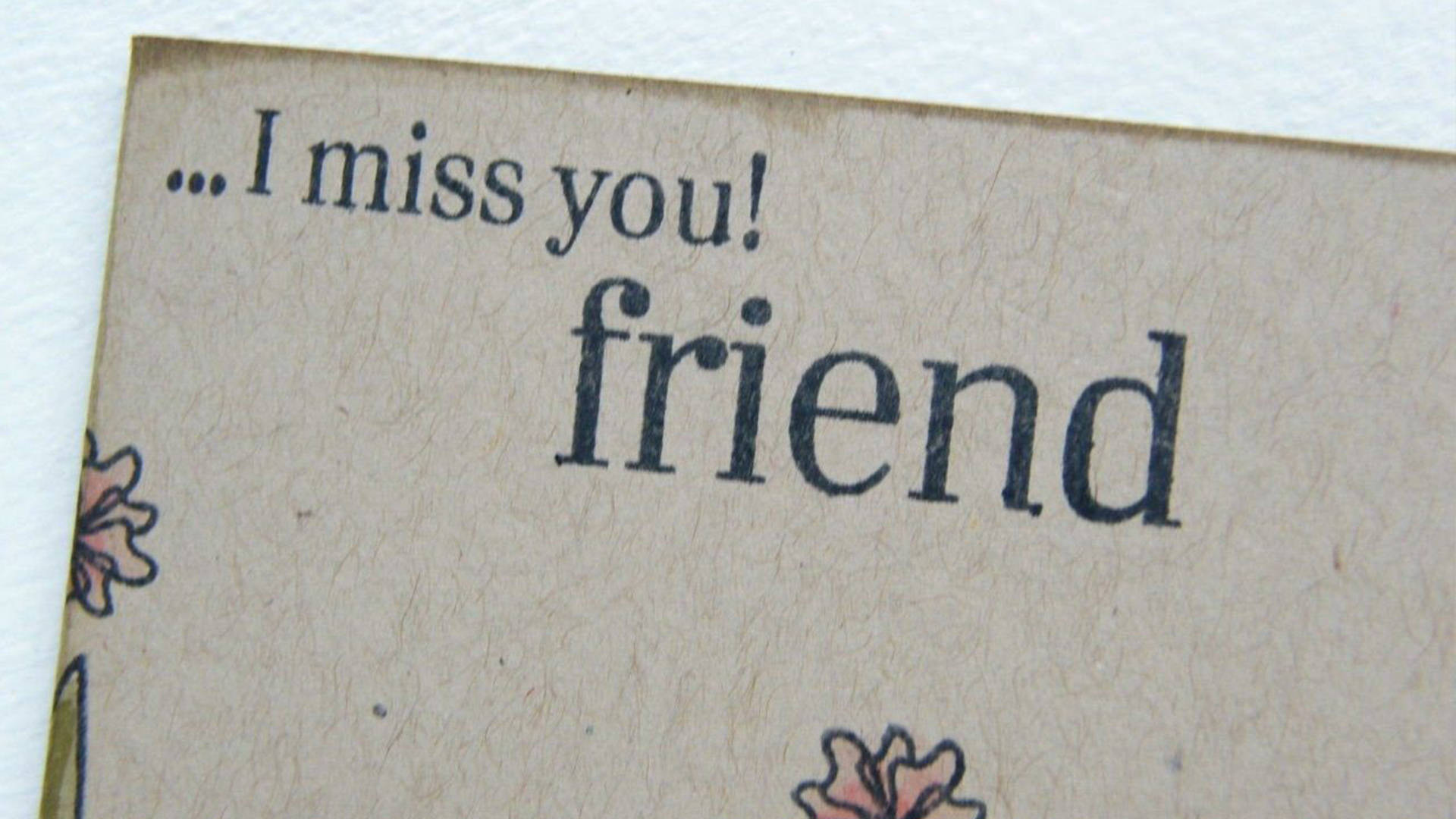 我想你 桌布 壁紙 — 手工卡片的特寫，上面有文字 I miss you friend 和花卉塗鴉，採用有紋理的棕色紙張。