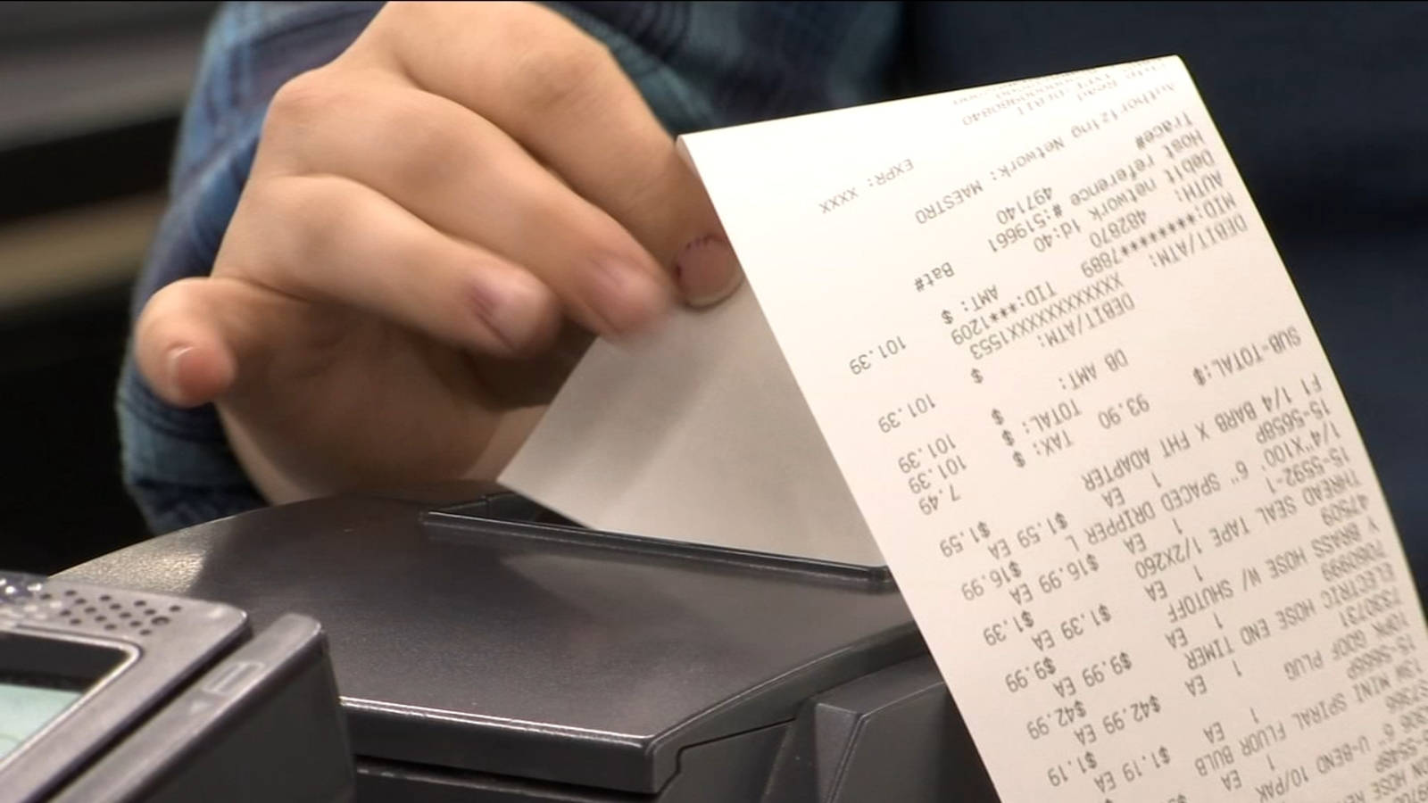 paper 桌布 壁紙 — 手從黑色收銀機拉出詳細收據的特寫，顯示產品價格和總額。