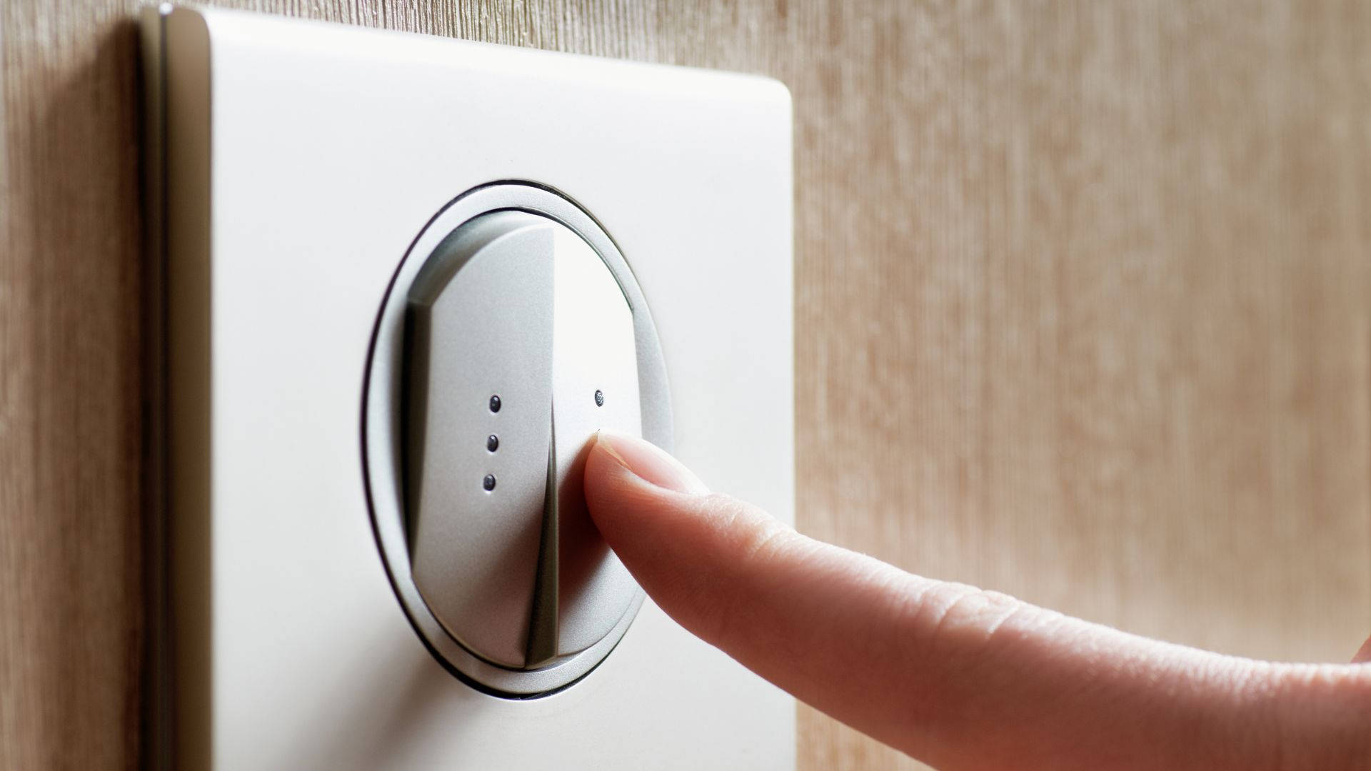 switch 桌布 壁紙 — 手指按下安裝在米色牆上的現代銀色翹板開關的特寫。
