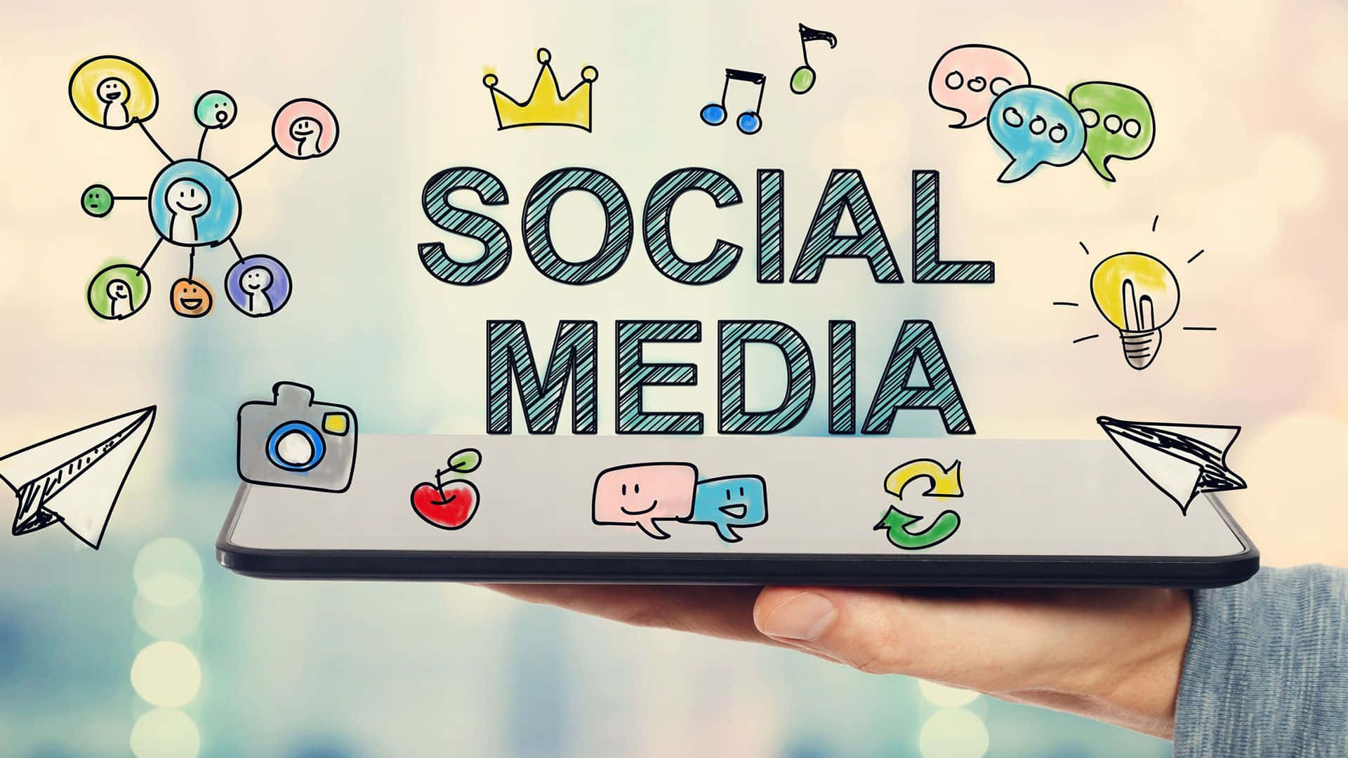 Application 桌布 壁紙 — 手握住智慧型手機，顯示 'SOCIAL MEDIA'，周圍漂浮著塗鴉圖標，背景是模糊的城市。