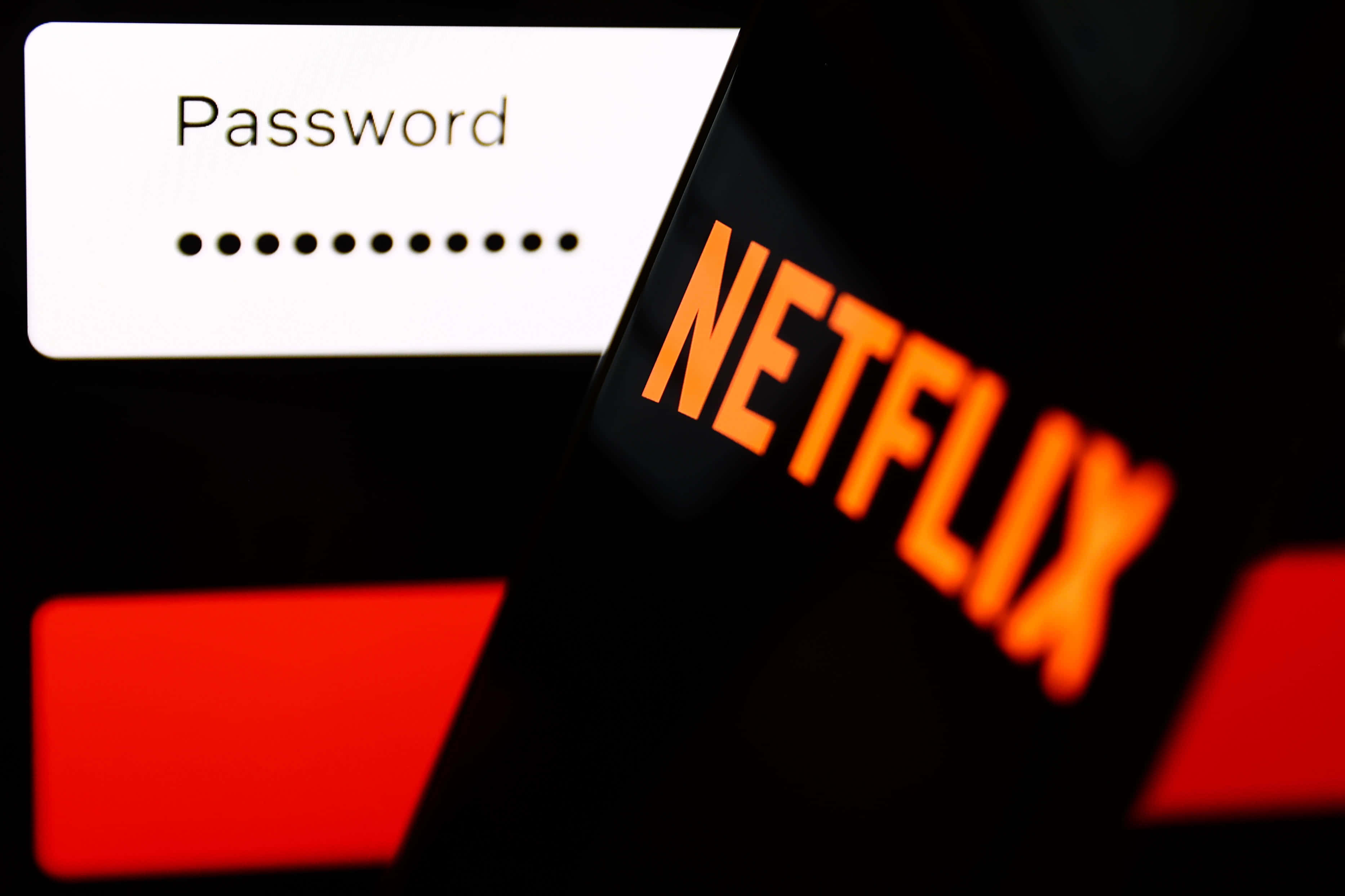 Netflix 桌布 壁紙 — 手機特寫顯示 Netflix 登入畫面，帶有密碼欄位和發光的橙色標誌，背景為深色。