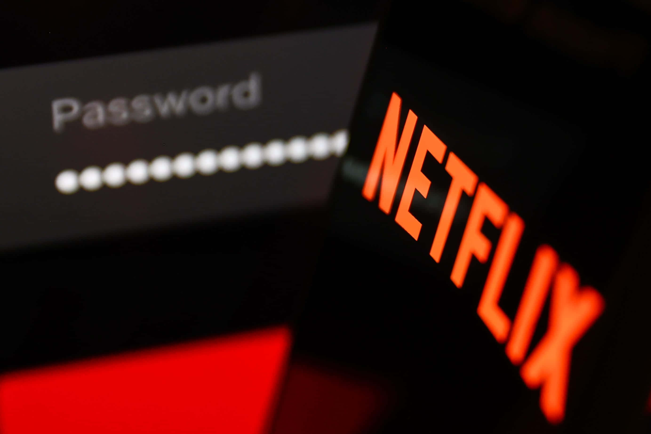 Netflix 桌布 壁紙 — 手機特寫顯示Netflix登入畫面，帶有發光的橙色標誌和密碼欄位。