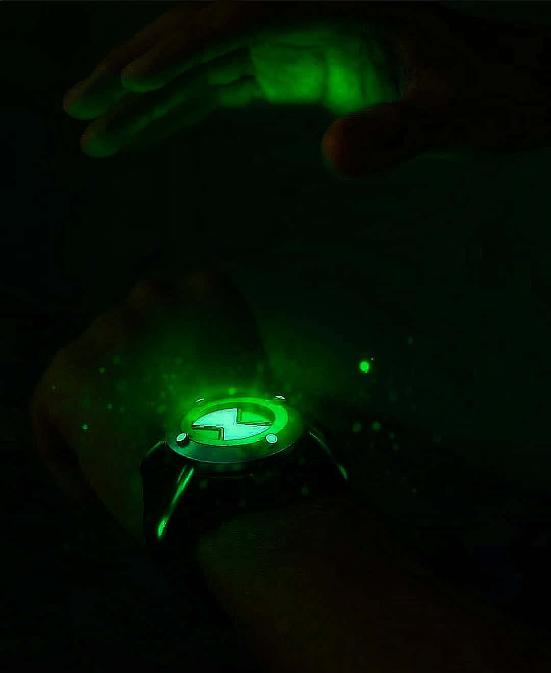 Ben 10 桌布 壁紙 — 手腕上發光的綠色 Omnitrix 手錶，以閃爍粒子照亮黑暗中的手。