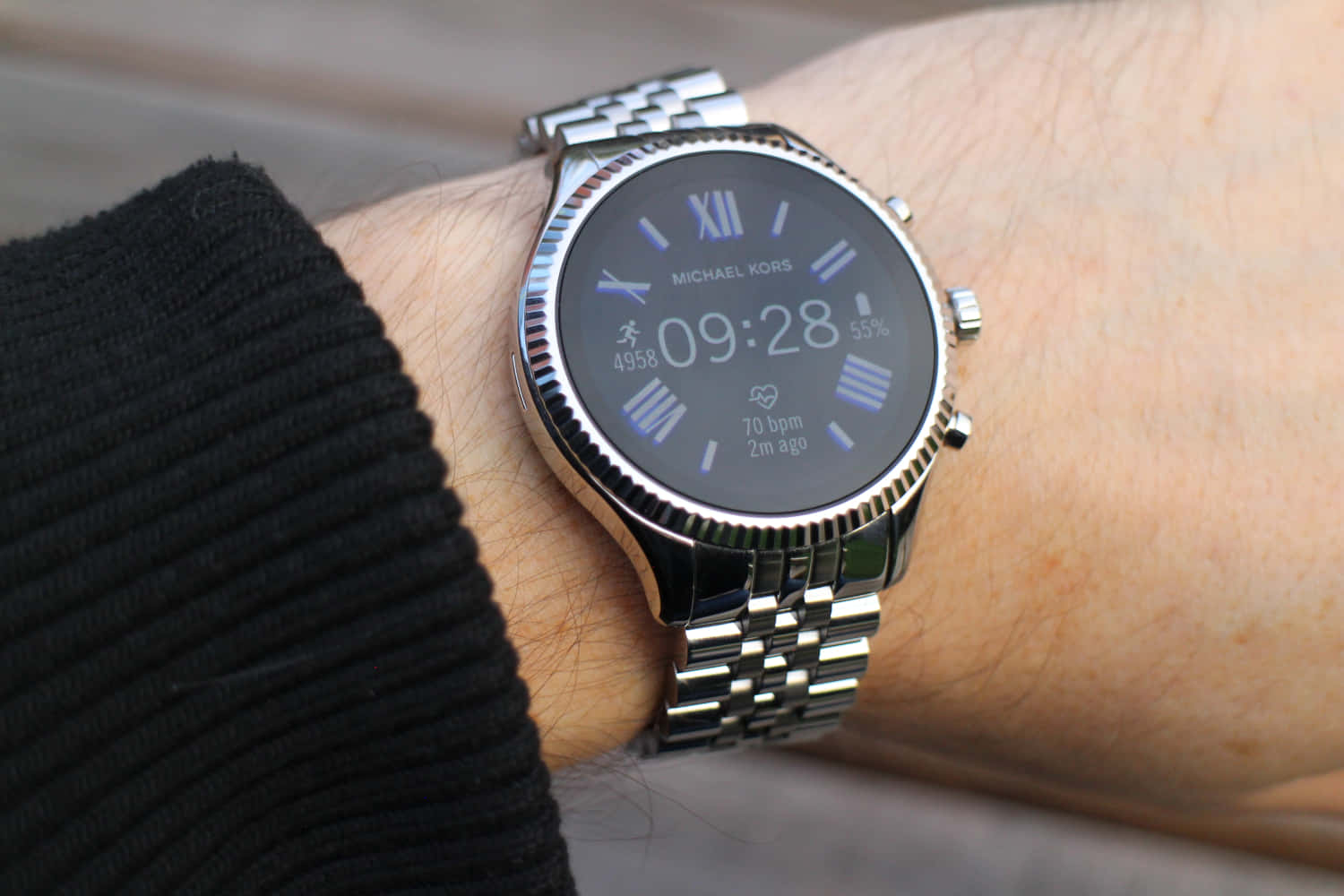 麥可·寇斯 桌布 壁紙 — 手腕上銀色 Michael Kors 智慧手錶的特寫，顯示時間、步數、心率和電池壽命。