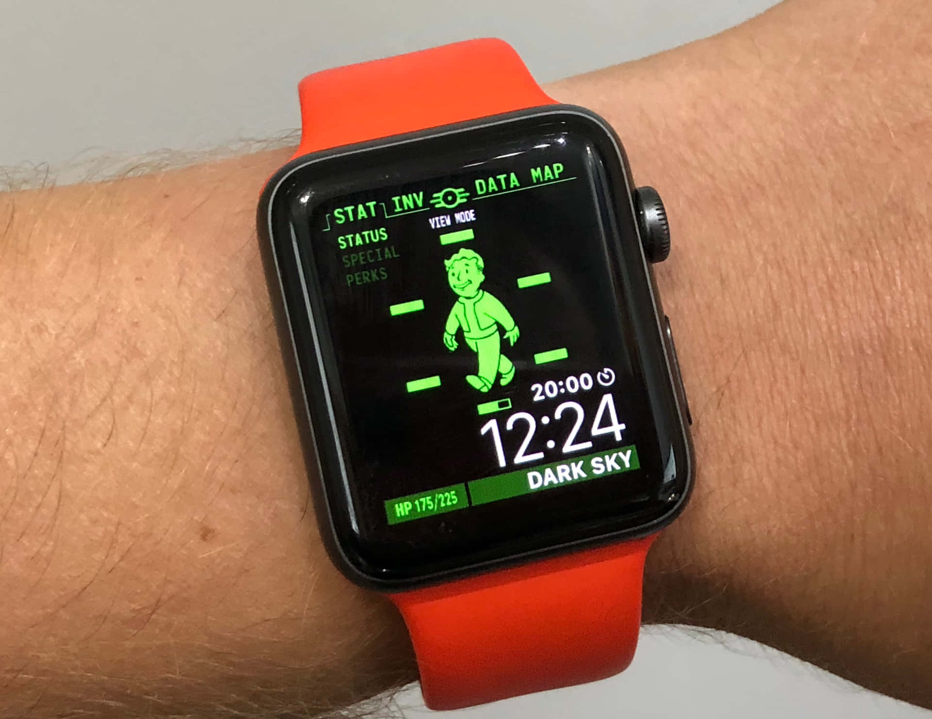帶橙色錶帶的智慧手錶在手腕上顯示Fallout遊戲介面。 — Apple Watch 動態 壁紙