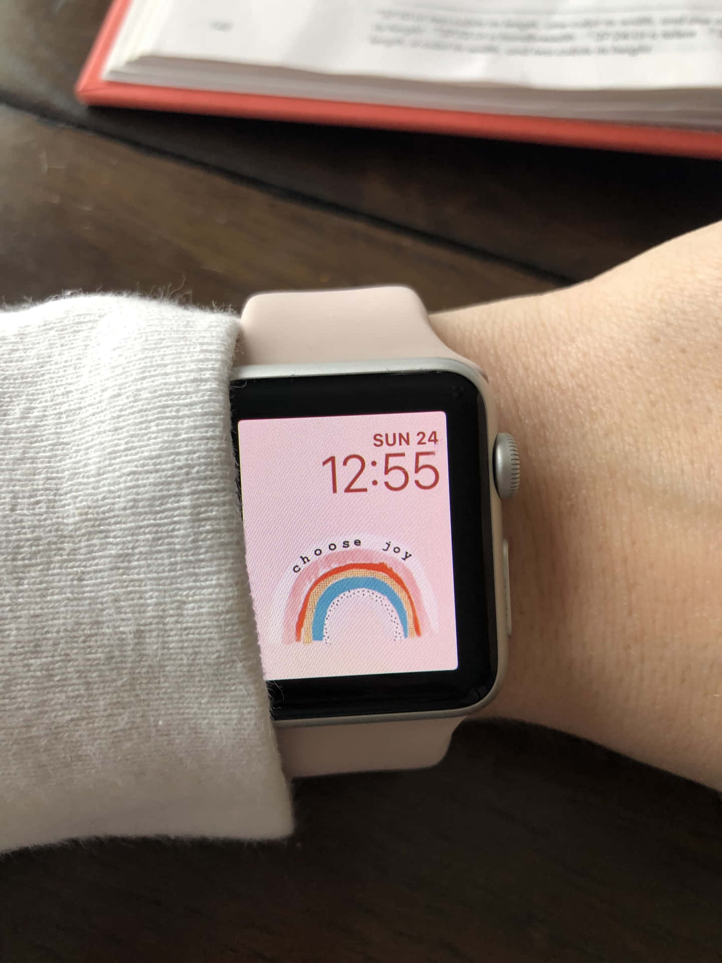 智慧手錶在粉紅色背景上顯示彩虹和短語選擇快樂。 — Apple Watch 動態 壁紙