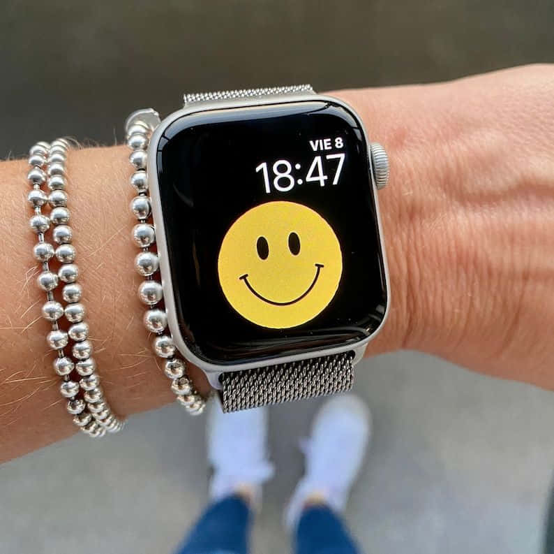 手腕上的 Apple Watch 顯示笑臉和銀色串珠手鍊。 — Apple Watch 動態 壁紙
