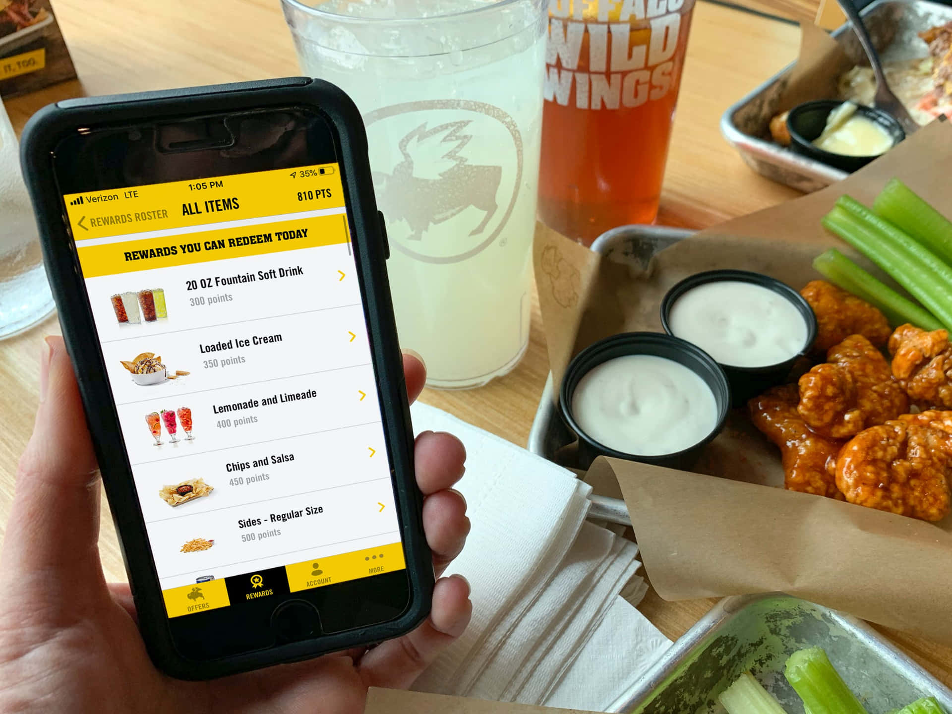 在Wild Wings餐廳用手機兌換獎勵，桌上放有雞翅和飲料。 — 水牛城辣雞翅 壁紙