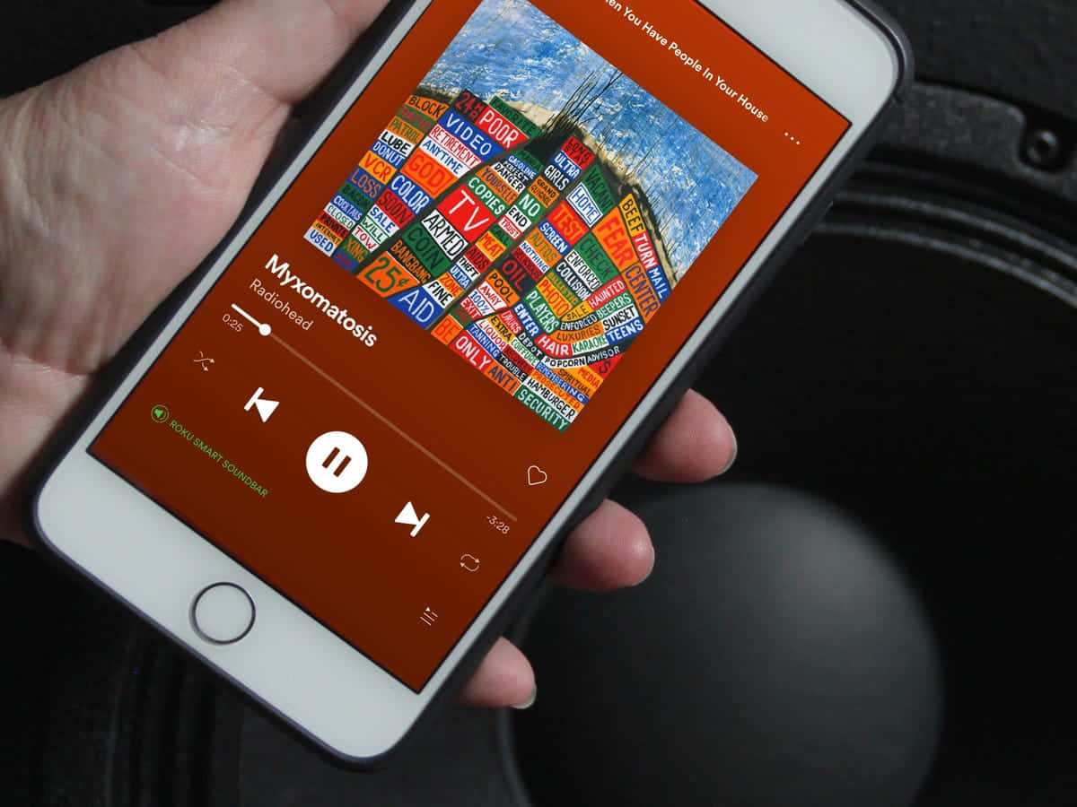 Screenshot 桌布 壁紙 — 手裡拿著智慧型手機，在車內播放 Radiohead 的 Myxomatosis，並帶有色彩繽紛的文字藝術專輯封面。
