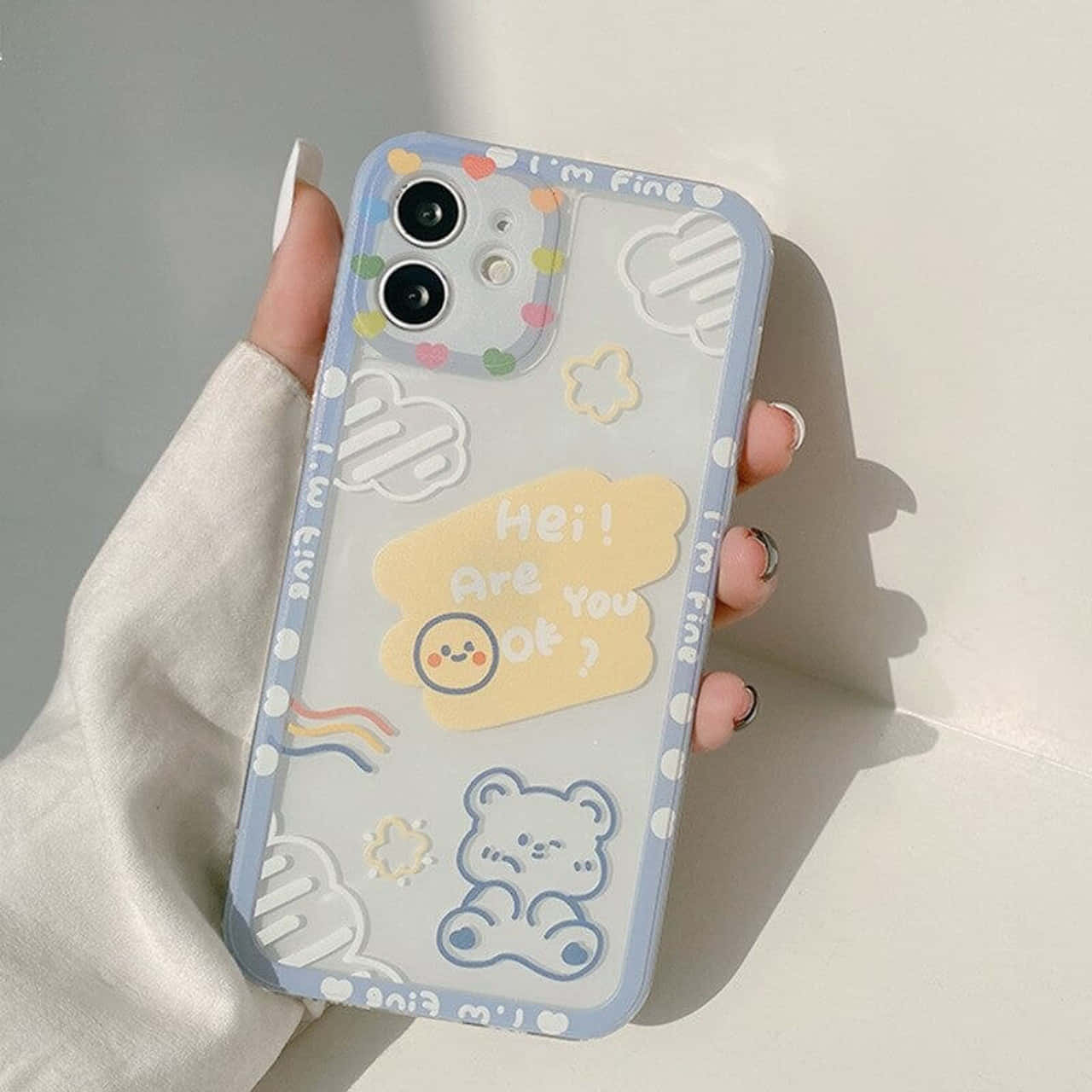 Phone Case 桌布 壁紙 — 手裡拿著透明手機殼，上面有可愛的藍色小熊、彩虹雲朵和「Hei Are You Ok？」文字設計。