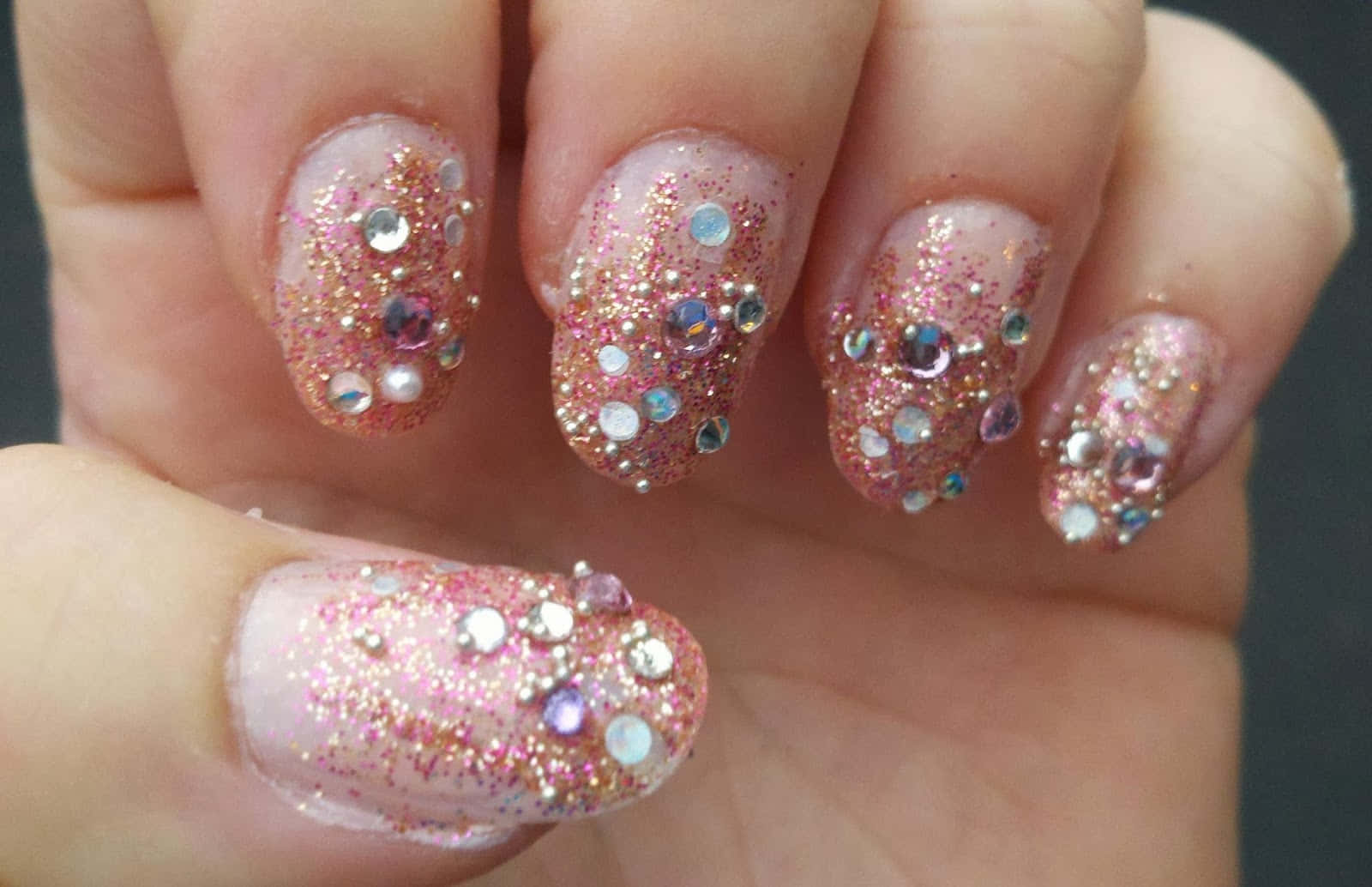 Pink Nails 桌布 壁紙 — 手部特寫，帶有閃粉粉紅指甲，飾以多色水鑽和金箔。