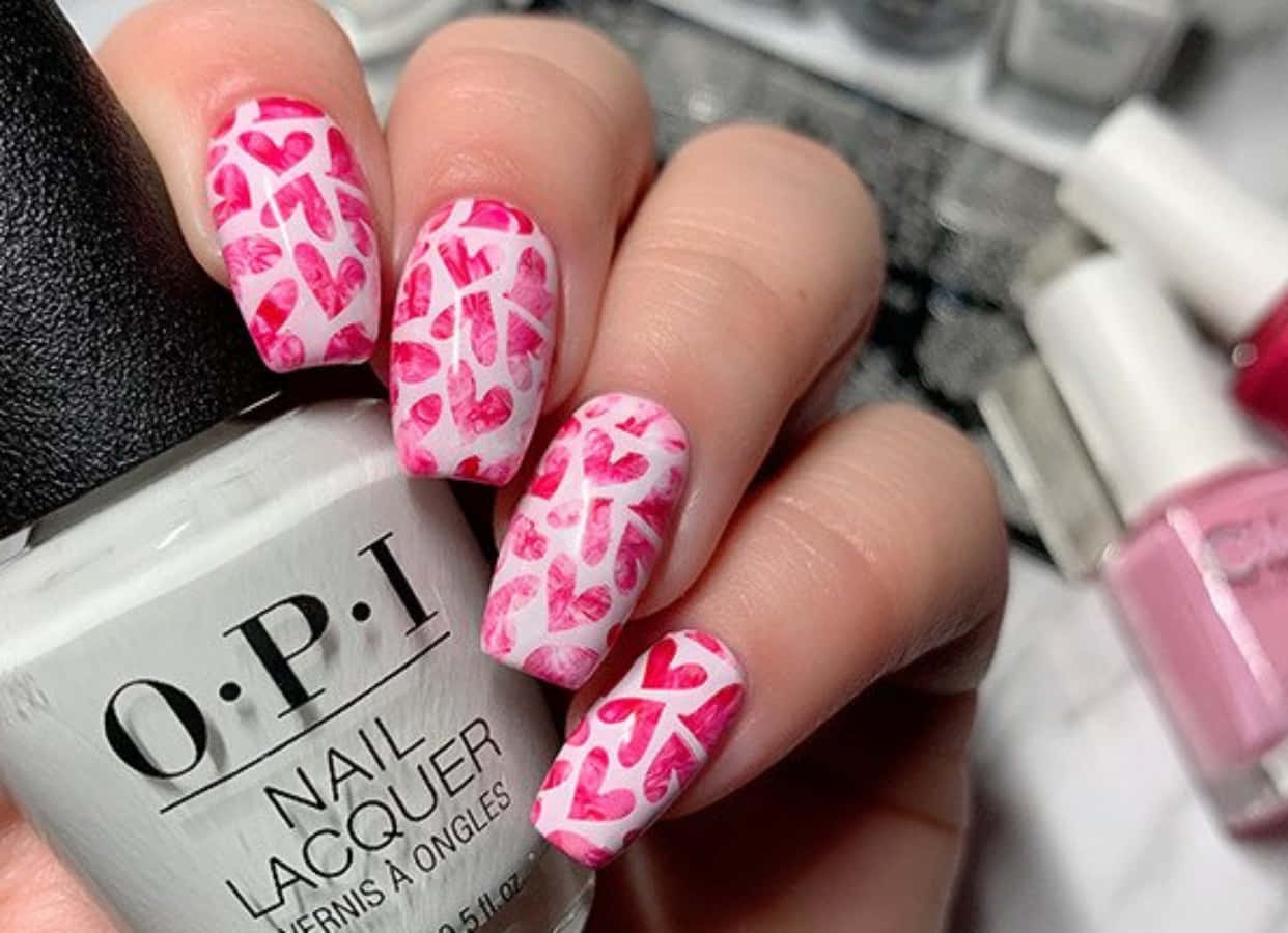 Pink Nail Art 桌布 壁紙 — 手部特寫，白色指甲上飾有粉紅色心形圖案，握著一瓶OPI指甲油。