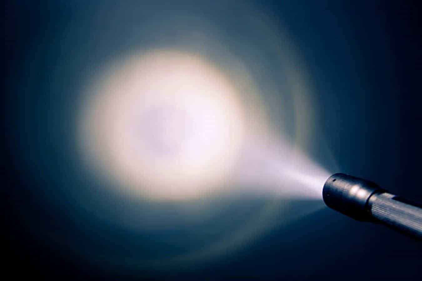 Flashlight 桌布 壁紙 — 手電筒光束穿透黑暗，在深藍色背景上投射出明亮的圓形光芒。