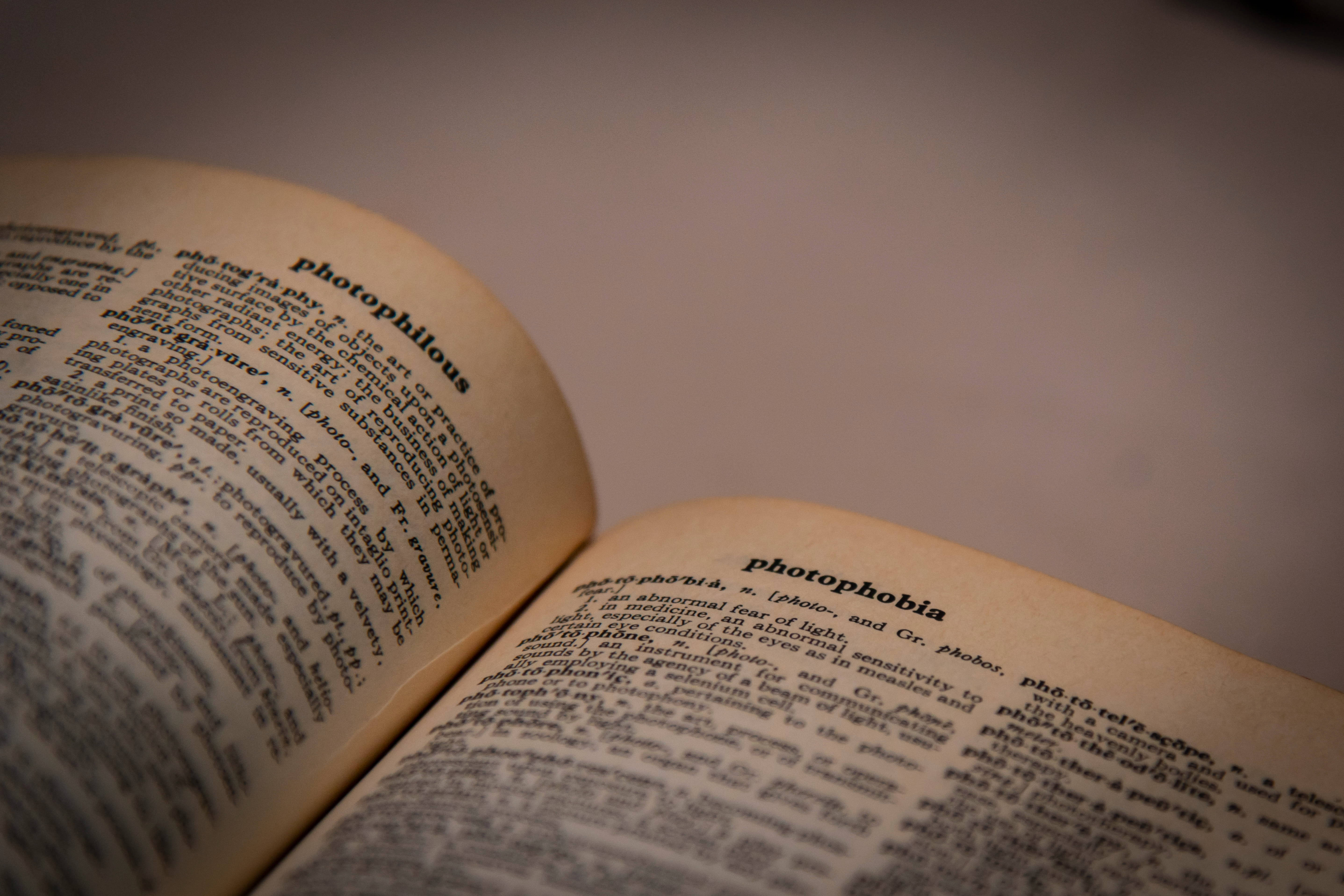 Dictionary 桌布 壁紙 — 打開的字典特寫，顯示 photophilous 和 photophobia 的條目，帶有柔和溫暖的光線。