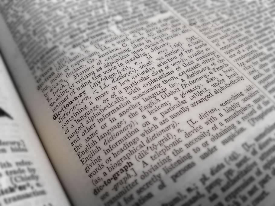 Dictionary 桌布 壁紙 — 打開的字典頁面的特寫，'dictionary' 這個字以粗體突出顯示，有密集的文字和角落模糊的筆尖。