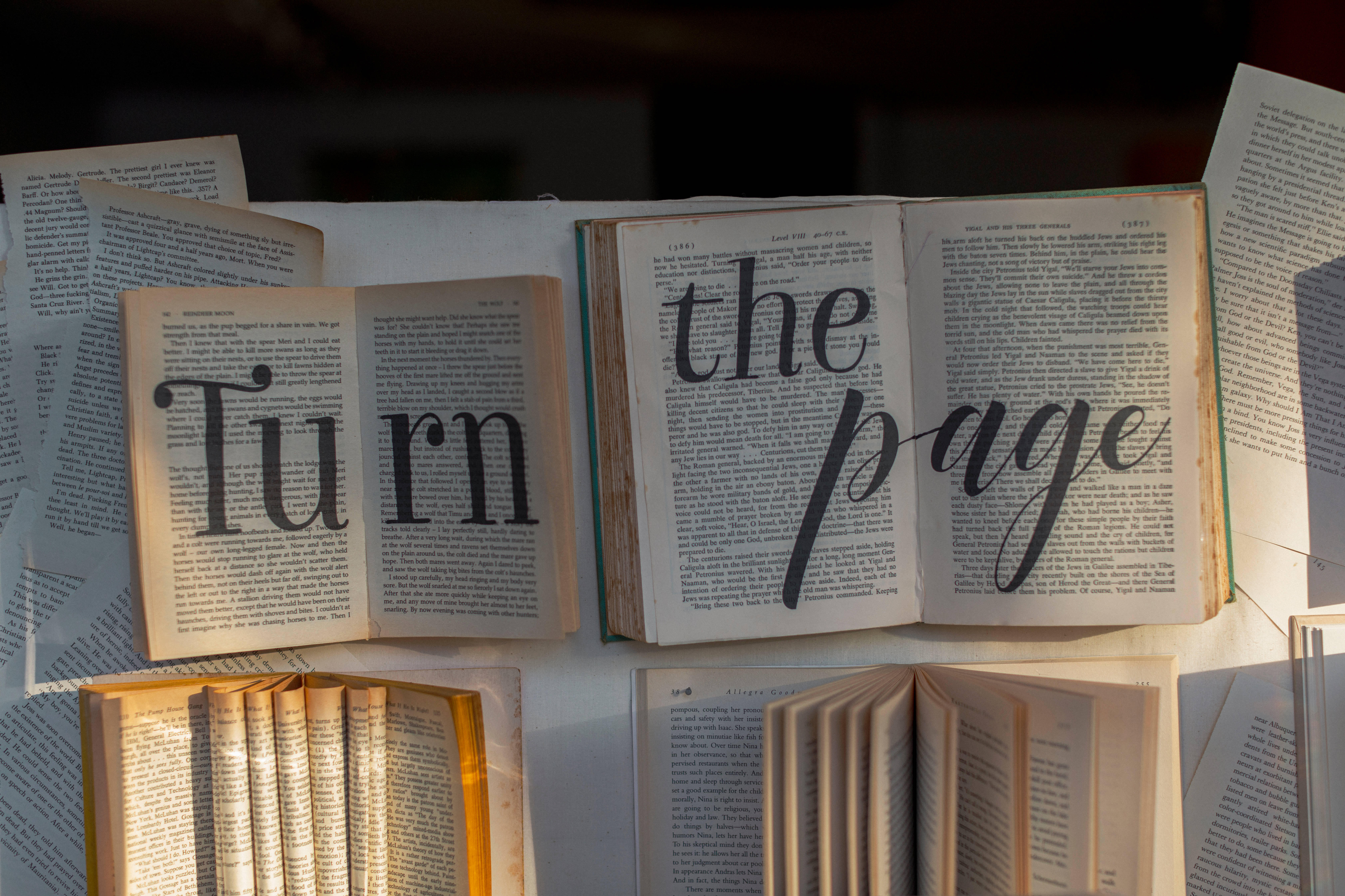 書本美學 桌布 壁紙 — 打開的書本帶有 'Turn the page' 文字疊加，排列在陽光照耀的木質表面上。
