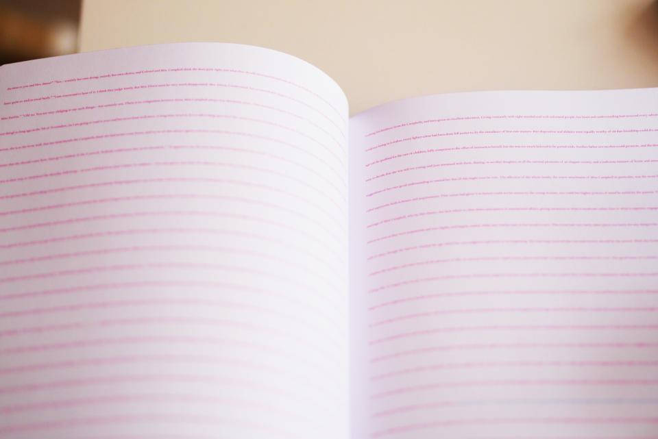 Notebook 桌布 壁紙 — 打開的書本特寫，白色頁面上有粉紅色文字，淺景深下柔和模糊。