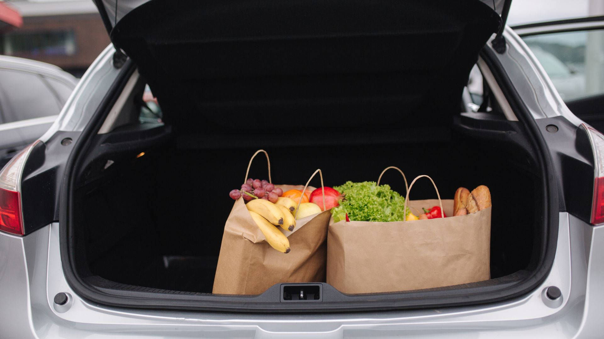 Fruits And Vegetables 桌布 壁紙 — 打開的汽車後車廂裝滿新鮮雜貨，放在棕色紙袋中，背景是明亮的日光。