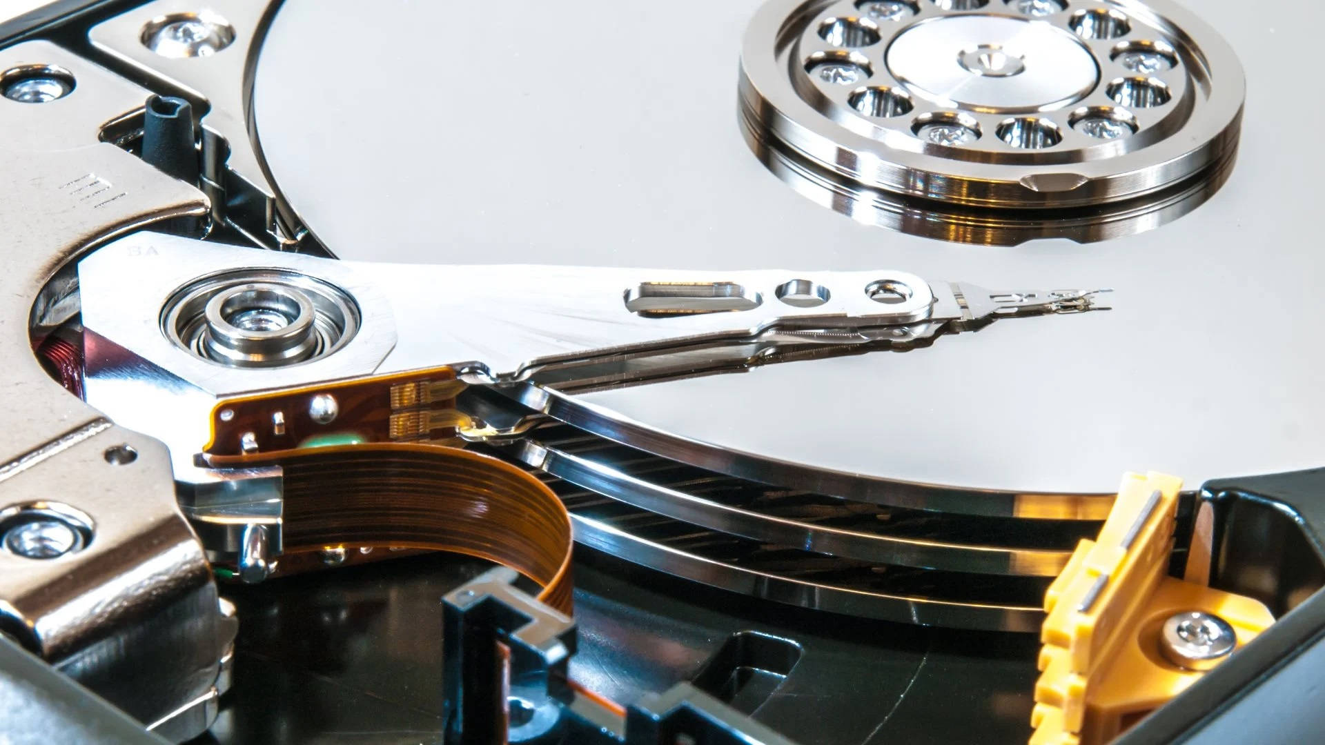 Hard Drive 桌布 壁紙 — 打開的硬碟機特寫，露出閃亮的碟片和帶有複雜機械細節的金屬讀寫臂。