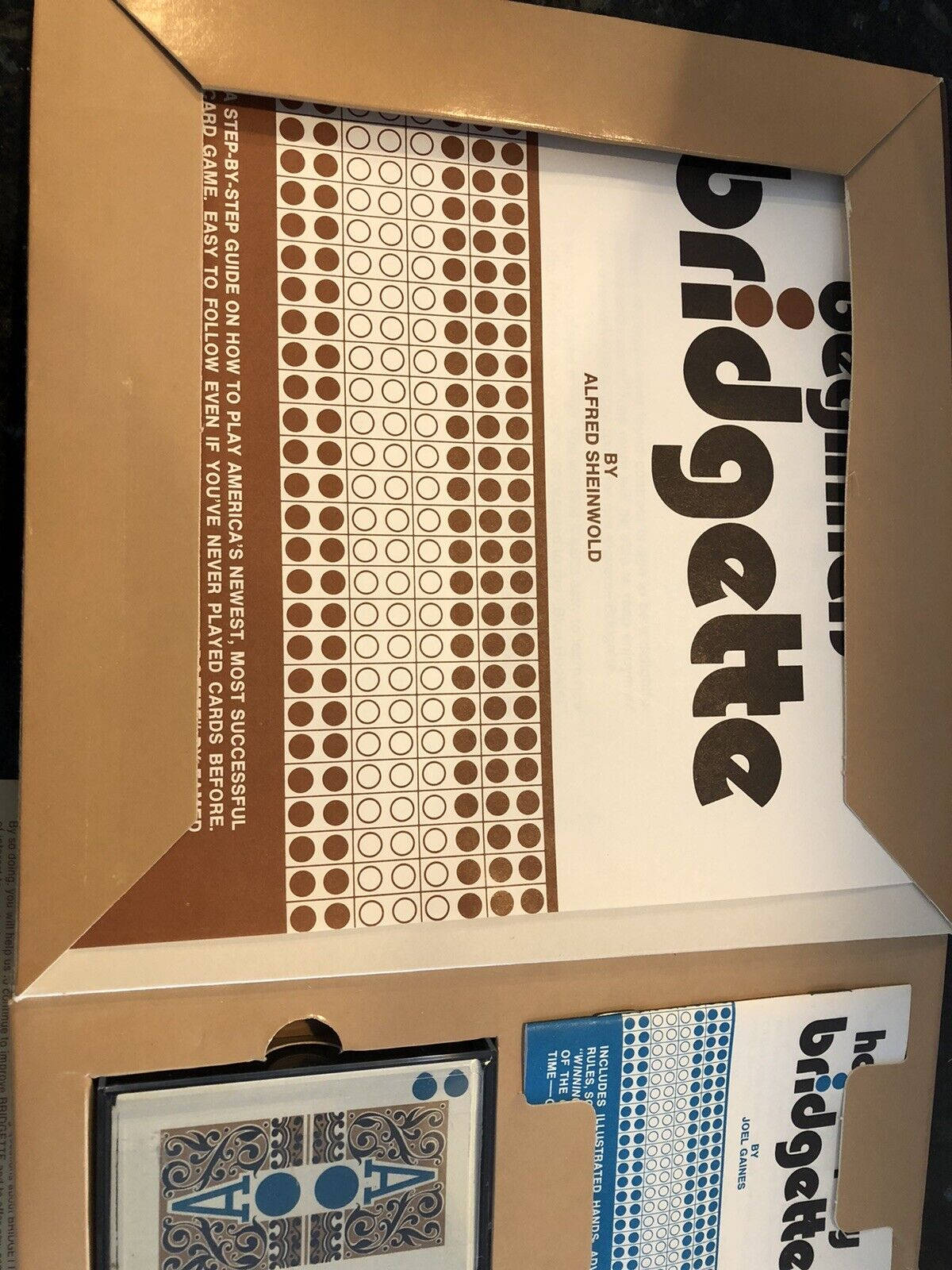 game 桌布 壁紙 — 打開的紙板箱露出「Bridgette」卡牌遊戲的內容，包括圖案內襯和插圖撲克牌。