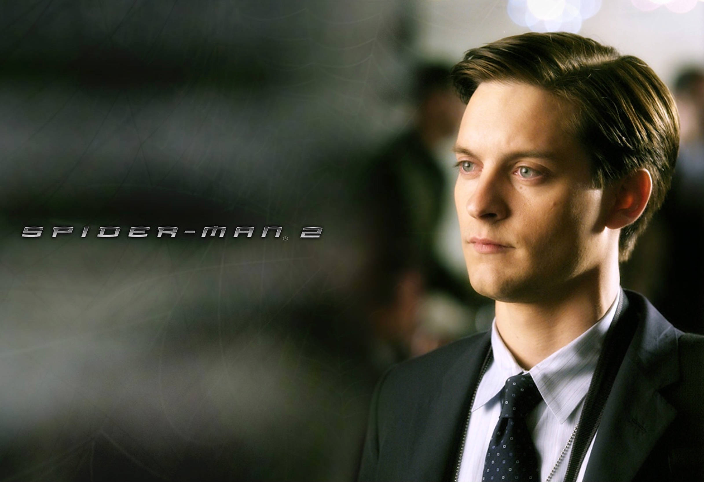Tobey Maguire 桌布 壁紙 — 托比·麥奎爾在《蜘蛛人2》中飾演彼得·帕克的近距離特寫，背景模糊並疊加電影標題。
