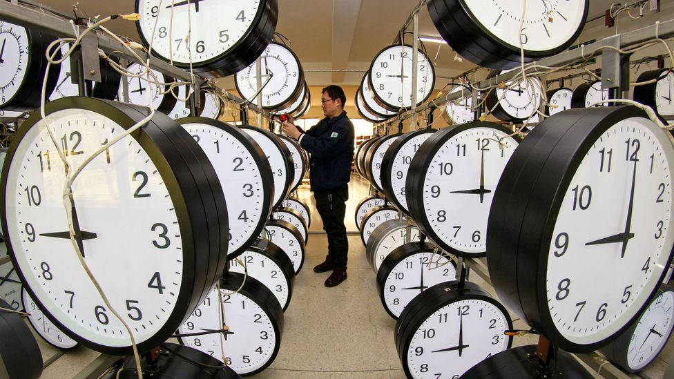 時鐘 桌布 壁紙 — 技術人員在一個掛滿指針時鐘的工廠裡調整時鐘。