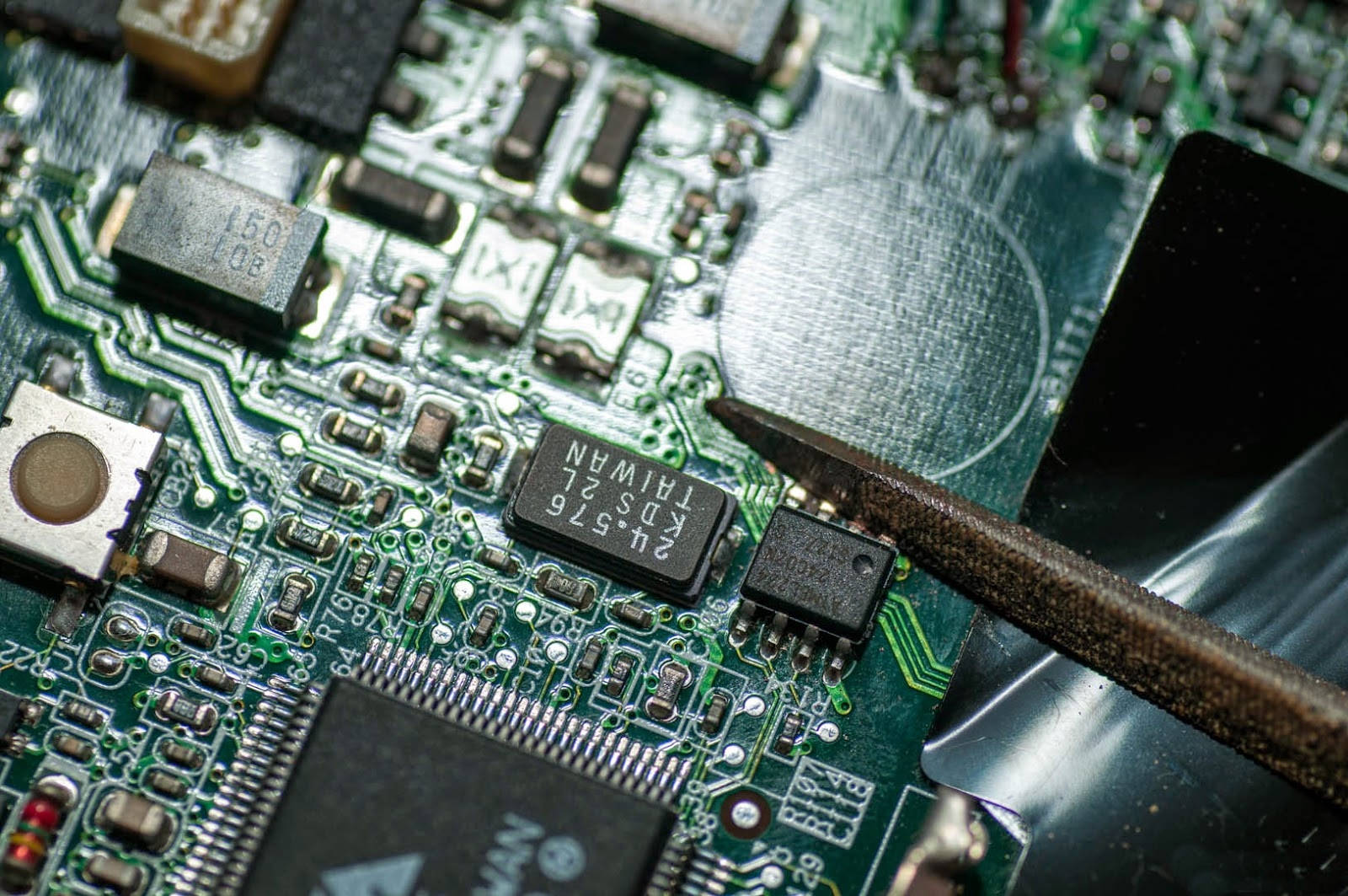 Motherboard 桌布 壁紙 — 技術人員的烙鐵觸碰帶有標籤晶片和複雜銅線路的綠色電路板的特寫。