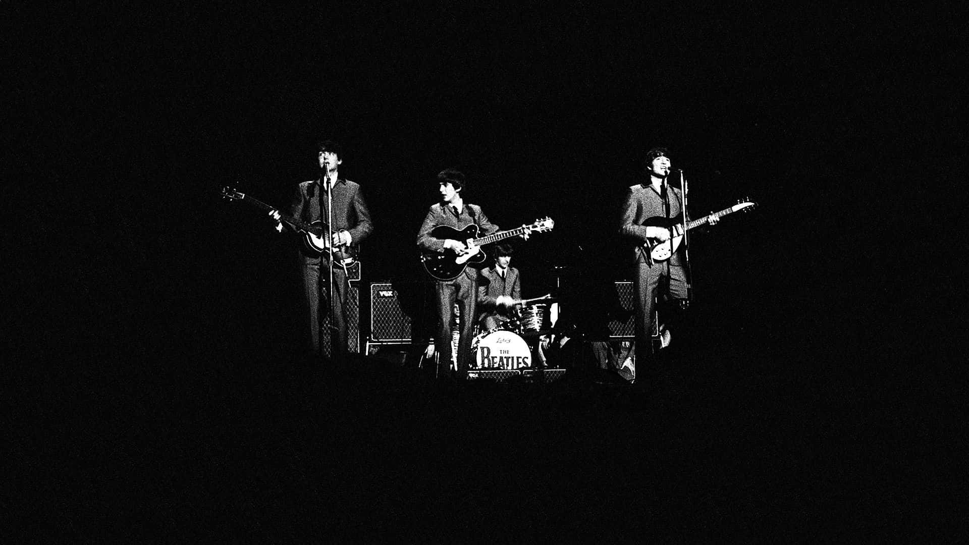 the beatles 桌布 壁紙 — 披頭四在黑色背景前以黑白風格表演，戲劇性的聚光燈照射。
