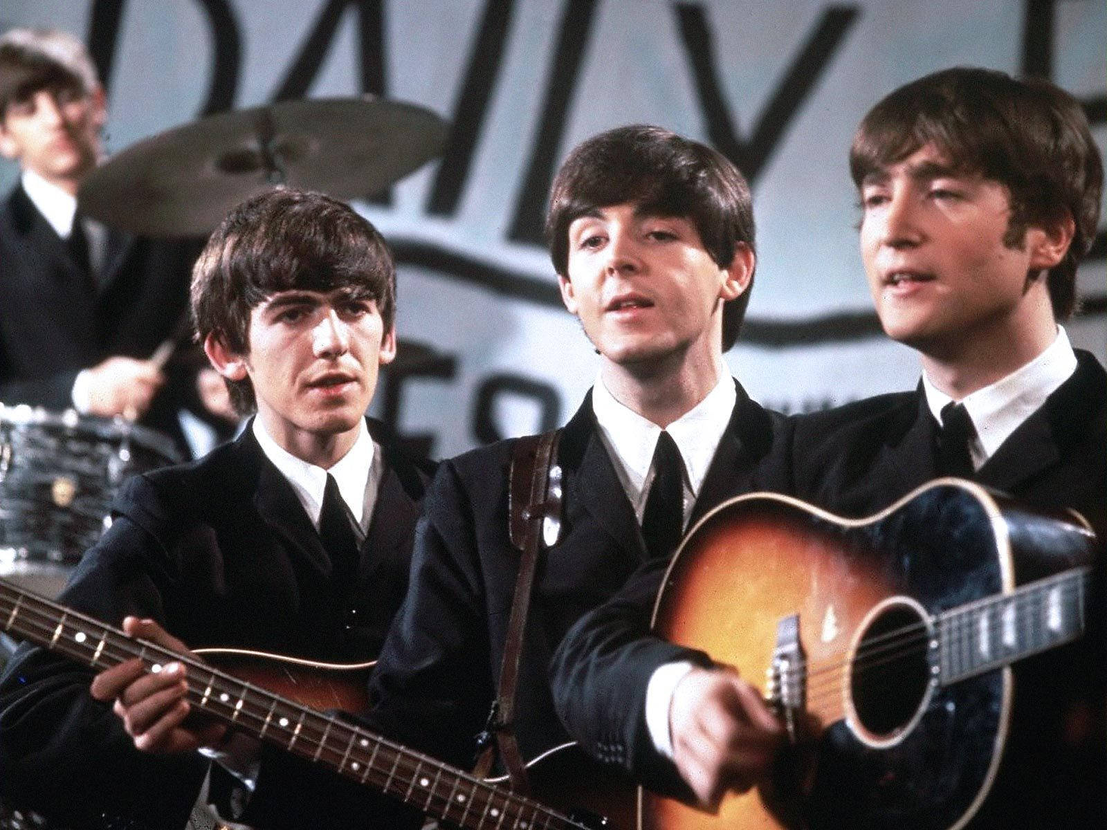 the beatles 桌布 壁紙 — 披頭四穿著俐落西裝，以原聲吉他和鼓現場演出，背景為粗體字樣。