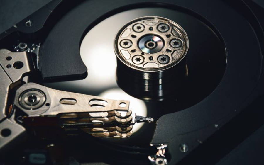 Hard Drive 桌布 壁紙 — 拆解硬碟的特寫，在戲劇性的燈光下顯露出其旋轉碟片和讀寫頭。