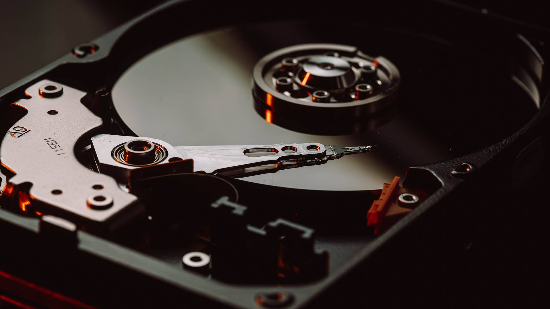 Hard Drive 桌布 壁紙 — 拆解硬碟的特寫，在戲劇性的紅光下顯露其旋轉碟片和讀寫頭。
