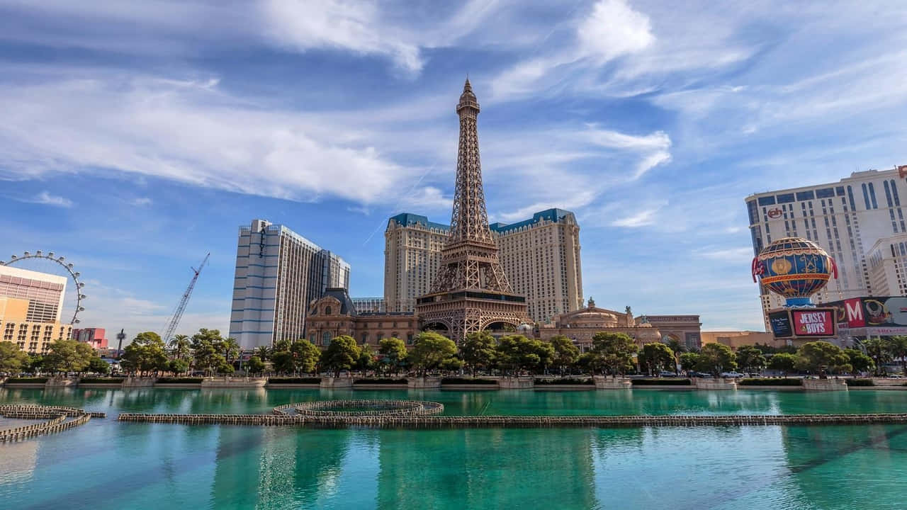 720p Las Vegas 桌布 壁紙 — 拉斯維加斯一座艾菲爾鐵塔複製品聳立在碧藍色泳池旁，天空湛藍，白雲點綴。