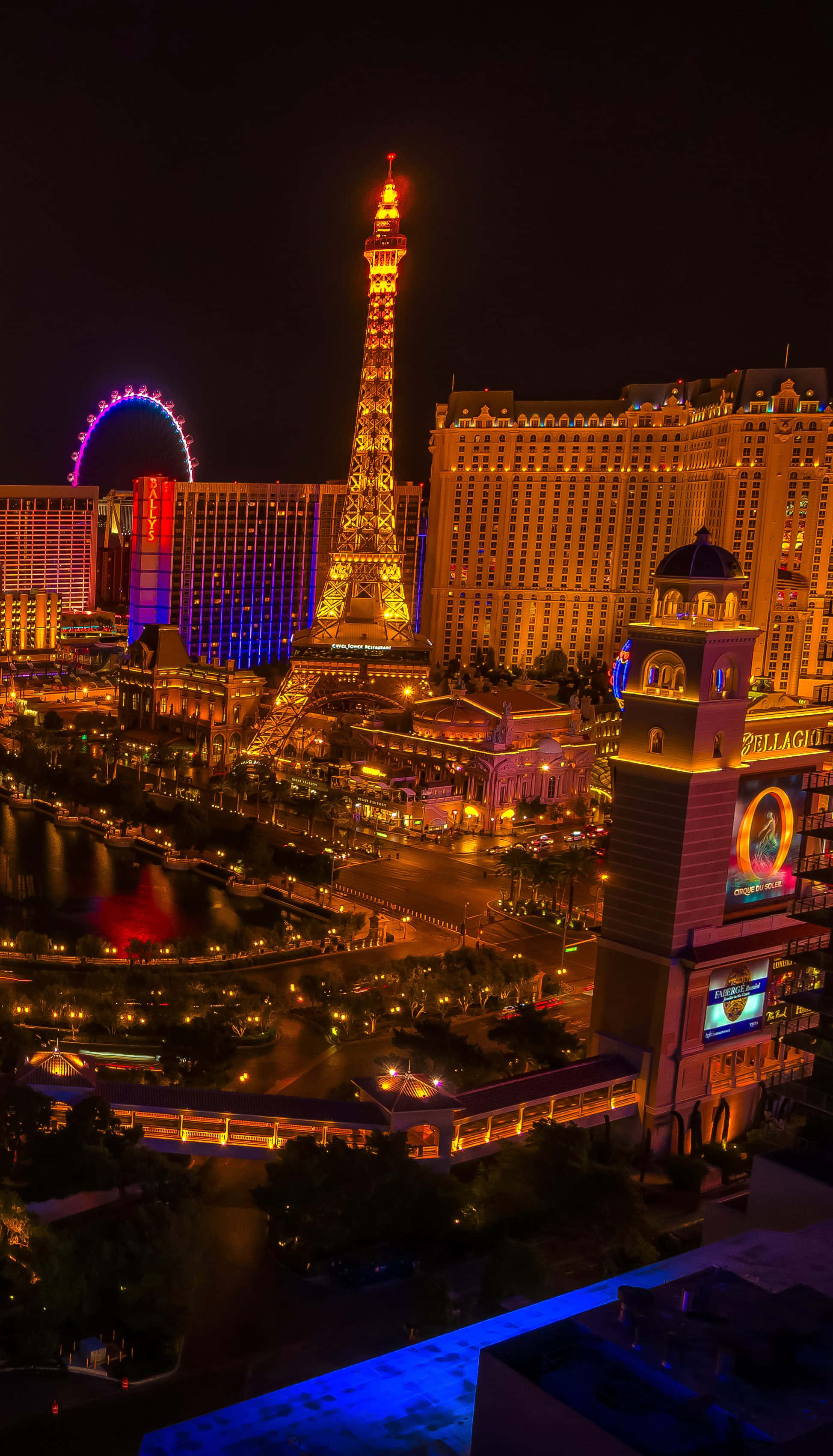 Las Vegas Phone 桌布 壁紙 — 拉斯維加斯令人目眩的夜景，展示了在黑暗天空下閃閃發光的艾菲爾鐵塔複製品和高滾輪摩天輪。