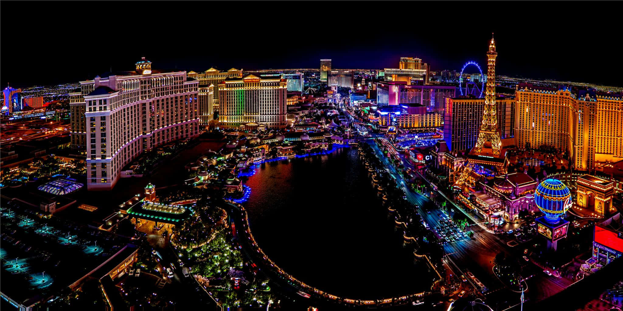 Las Vegas 桌布 壁紙 — 拉斯維加斯令人目眩的夜景，展示霓虹燈照亮的酒店和拉斯維加斯大道上標誌性的艾菲爾鐵塔複製品。