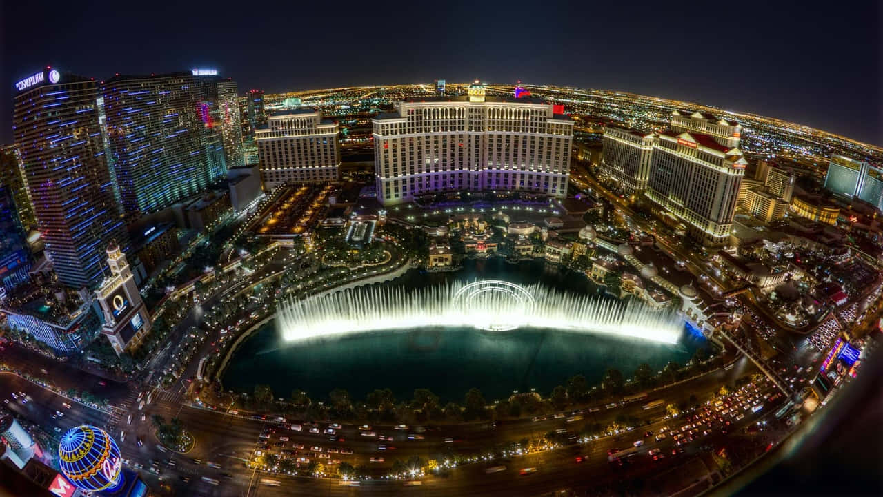 720p Las Vegas 桌布 壁紙 — 拉斯維加斯令人眼花撩亂的夜間魚眼景觀，展示了貝拉吉奧噴泉在摩天大樓和閃爍街道中與燈光共舞。