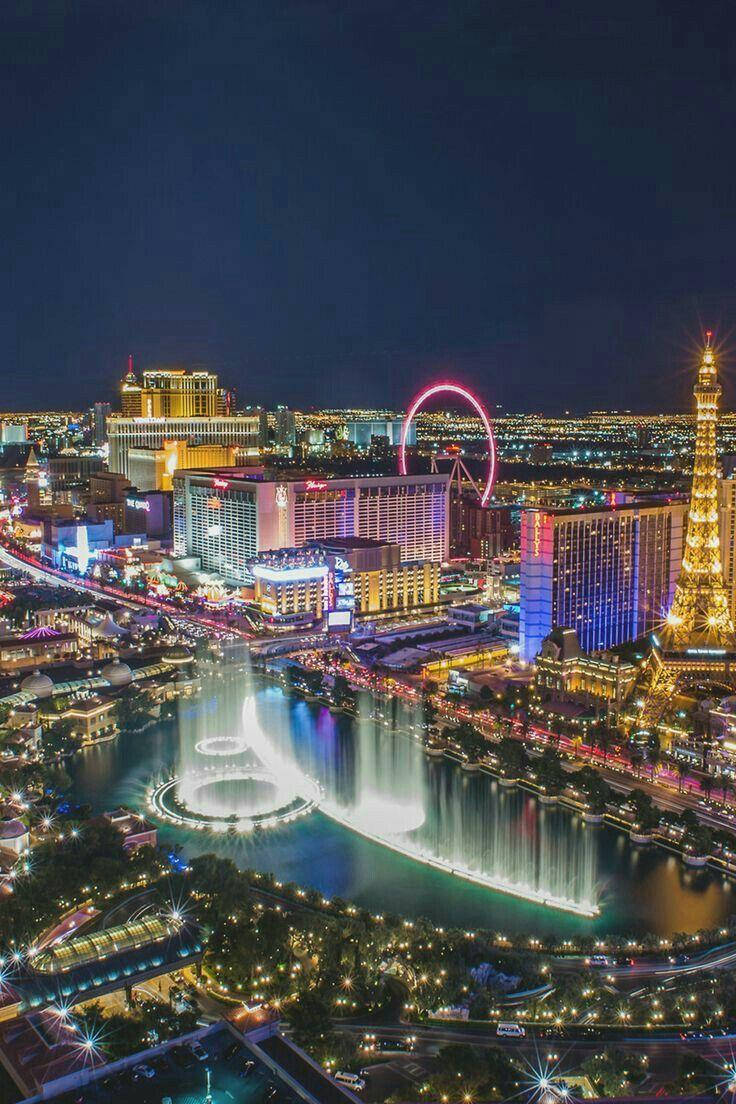 Vegas iPhone 桌布 壁紙 — 拉斯維加斯令人眼花撩亂的夜間鳥瞰圖，展示了燈光璀璨的噴泉、豪客摩天輪和艾菲爾鐵塔複製品。