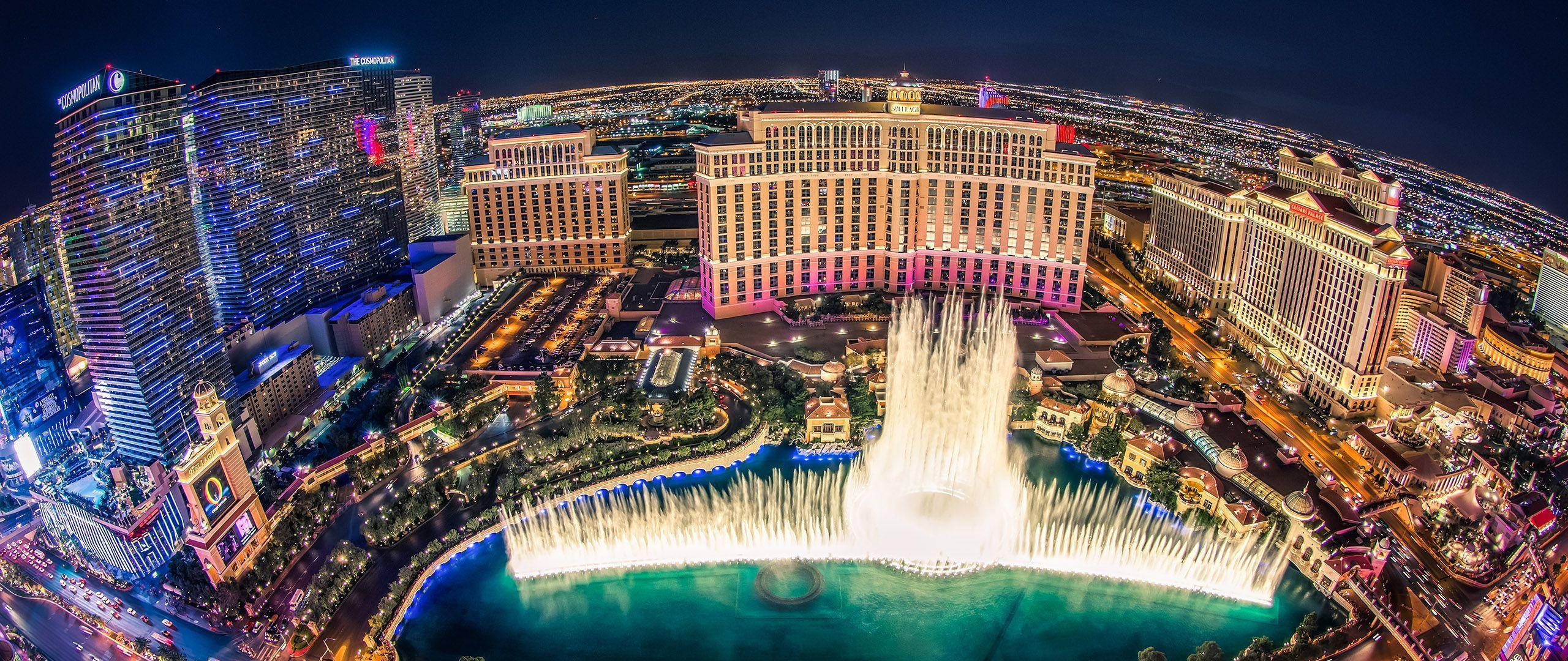 拉斯維加斯 桌布 壁紙 — 拉斯維加斯令人眼花繚亂的夜間鳥瞰圖，展示了貝拉吉奧噴泉在聳立的燈火輝煌酒店中伴隨著燈光翩翩起舞。