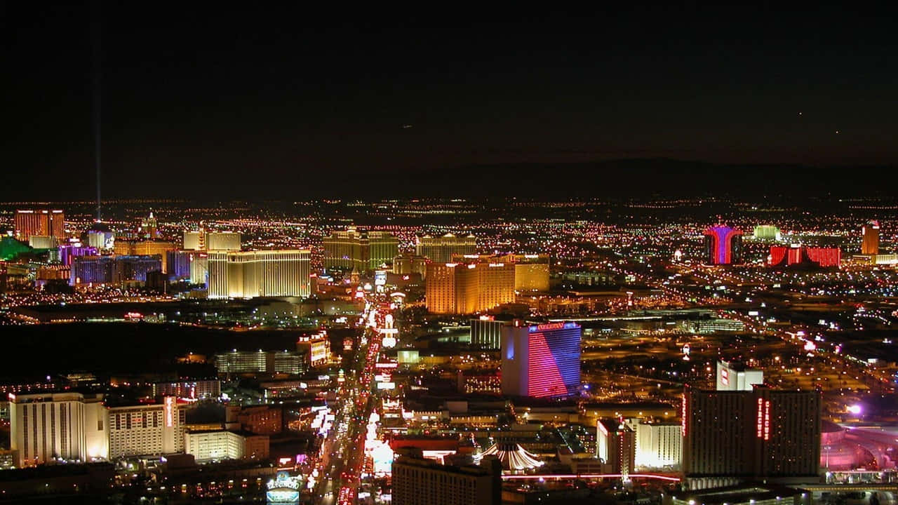 720p Las Vegas 桌布 壁紙 — 拉斯維加斯令人驚嘆的夜間空中景觀，展現了在黑暗天空下霓虹燈閃爍的酒店和繁忙的街道。